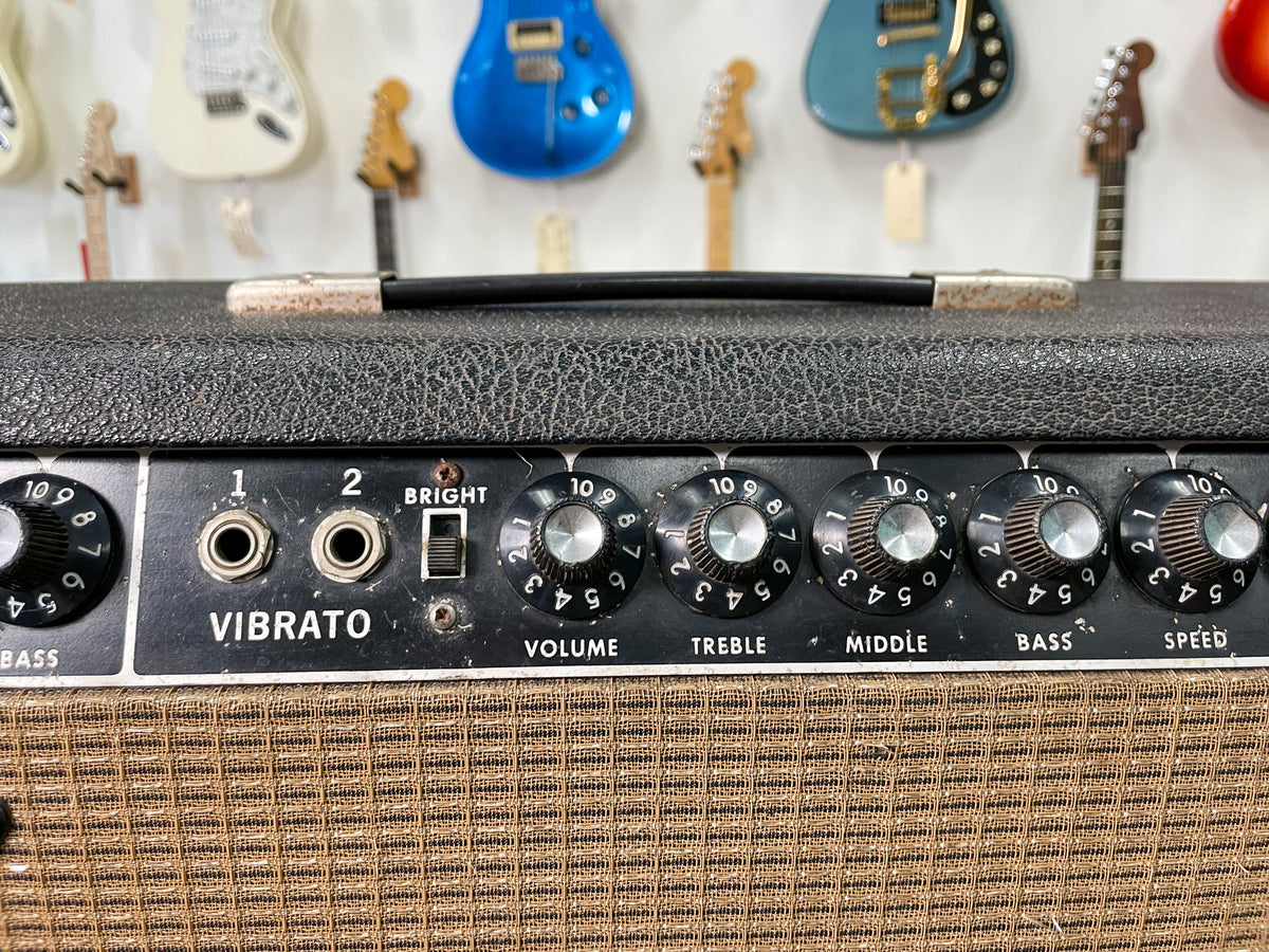 Close-up of the amp's black control panel with silver knobs, two input jacks, and a bright switch, showing some wear and dust.