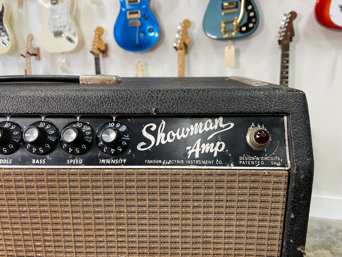 Close-up of the amp's black control panel and brown grille cloth, showing four black knobs, a red jewel light, and visible wear.