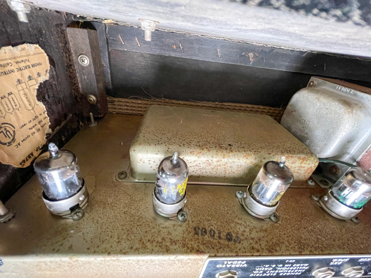 Top-down view of the amp's interior, showing four vacuum tubes, a large transformer, and a worn paper label.