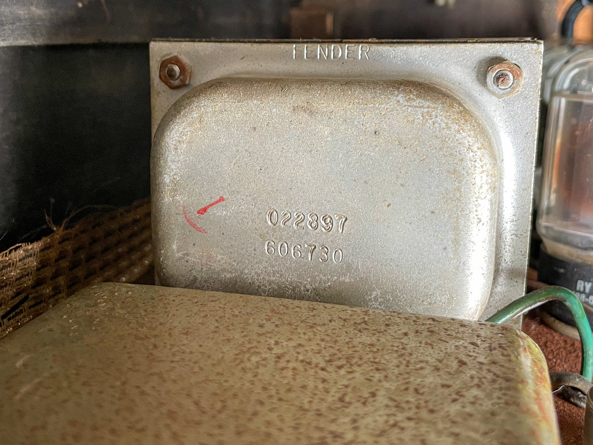 Close-up of the amp's silver-grey transformer, showing stamped numbers, a red mark, and visible rust on mounting bolts.