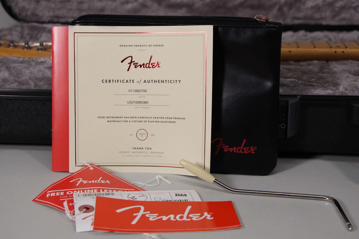 The guitar's certificate of authenticity, hang tags, and tremolo arm with a cream tip are displayed on a gray surface.