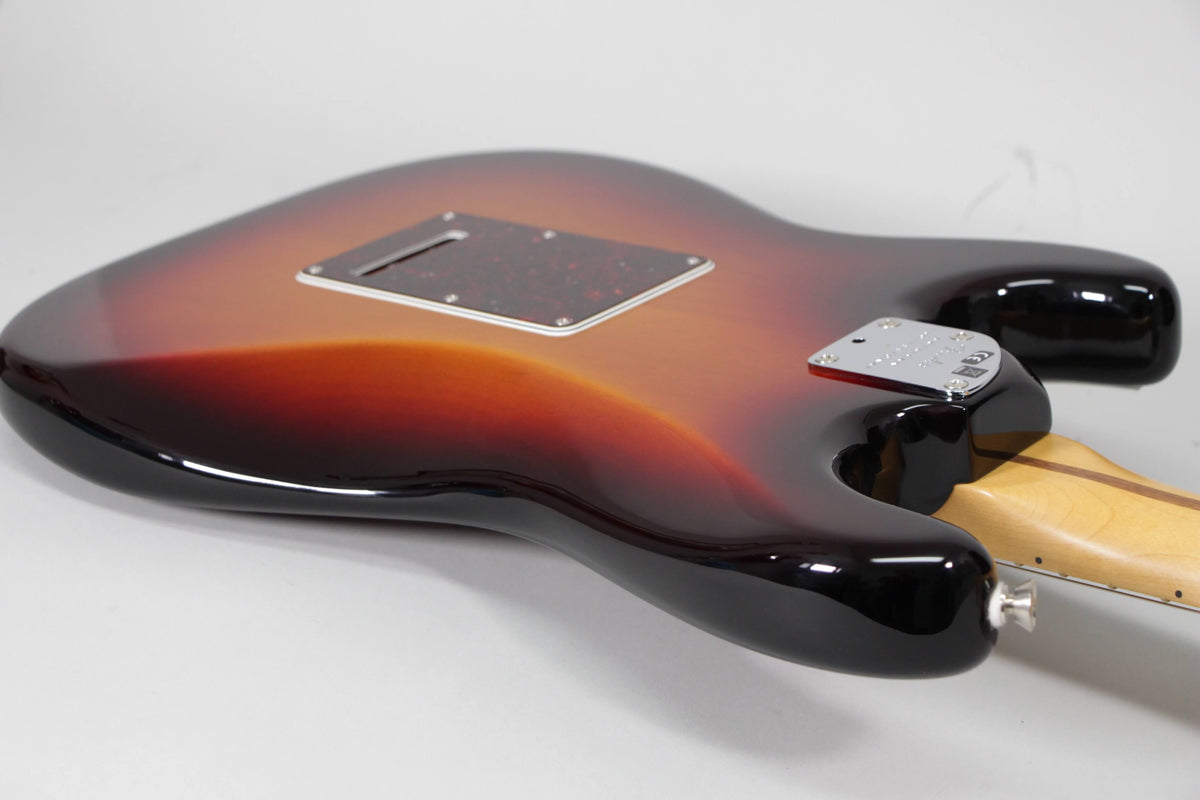 The guitar's sunburst back, with a tortoiseshell tremolo cover and chrome neck plate, is angled from the lower bout.