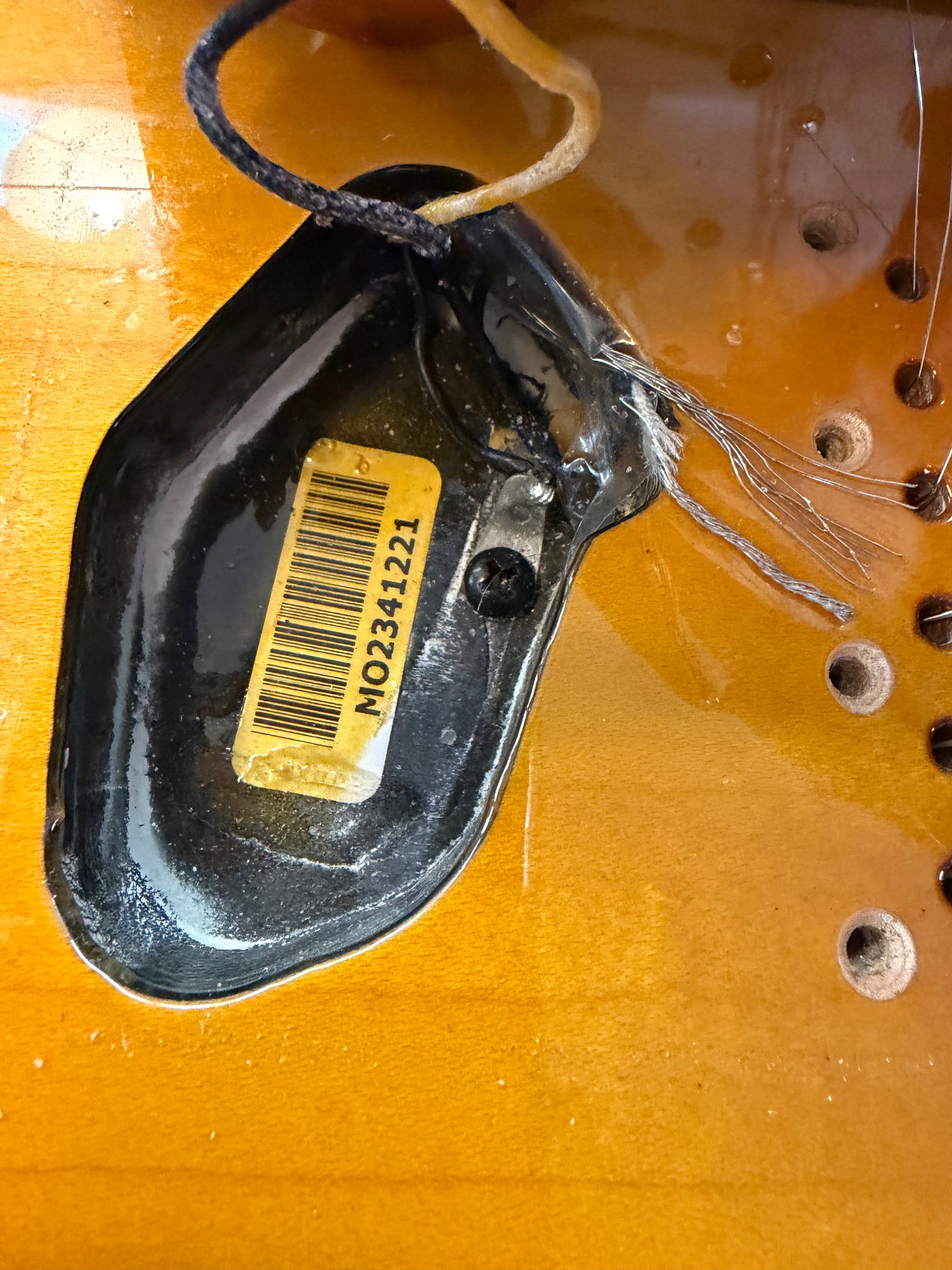 Close-up of the guitar's sunburst body cavity, showing a black pickup with a yellow barcode sticker and exposed wiring.