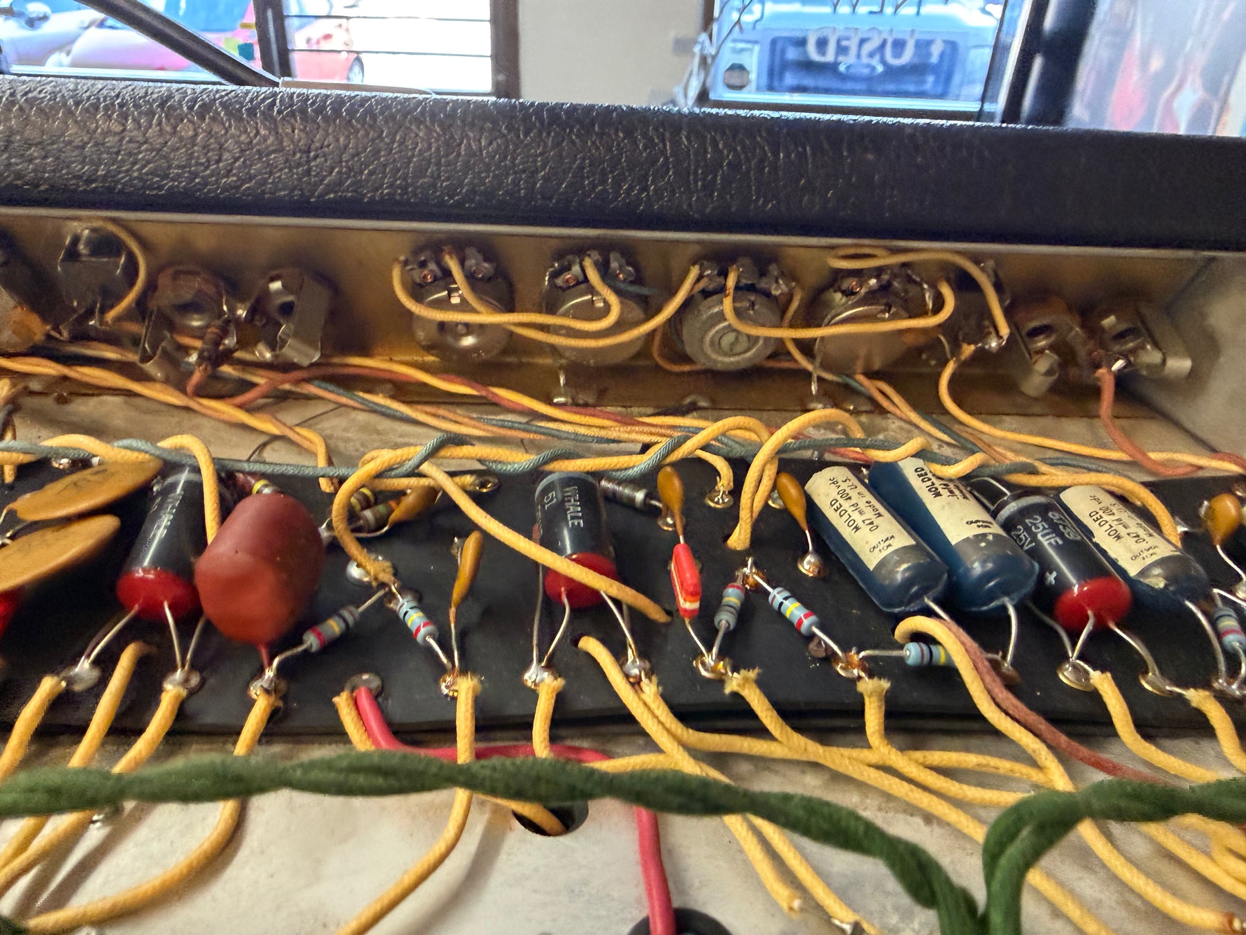 Close-up of the amp's internal wiring, showing numerous colorful capacitors, resistors, and yellow cloth-covered wires.