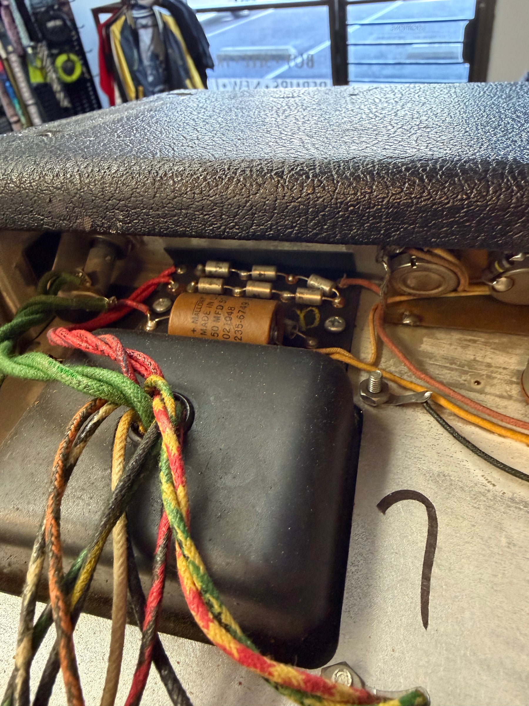 Close-up of the amp's internal wiring, showing colorful cloth-covered wires, a brown capacitor, and several small fuses.