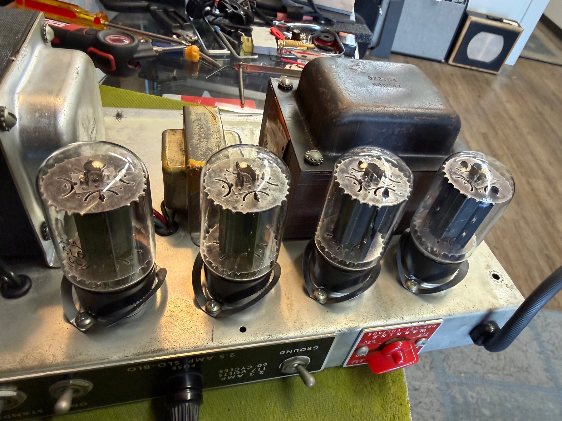 Close-up of the amp's chassis, showing four large vacuum tubes, two transformers, and a red voltage selector switch on a worn metal panel.