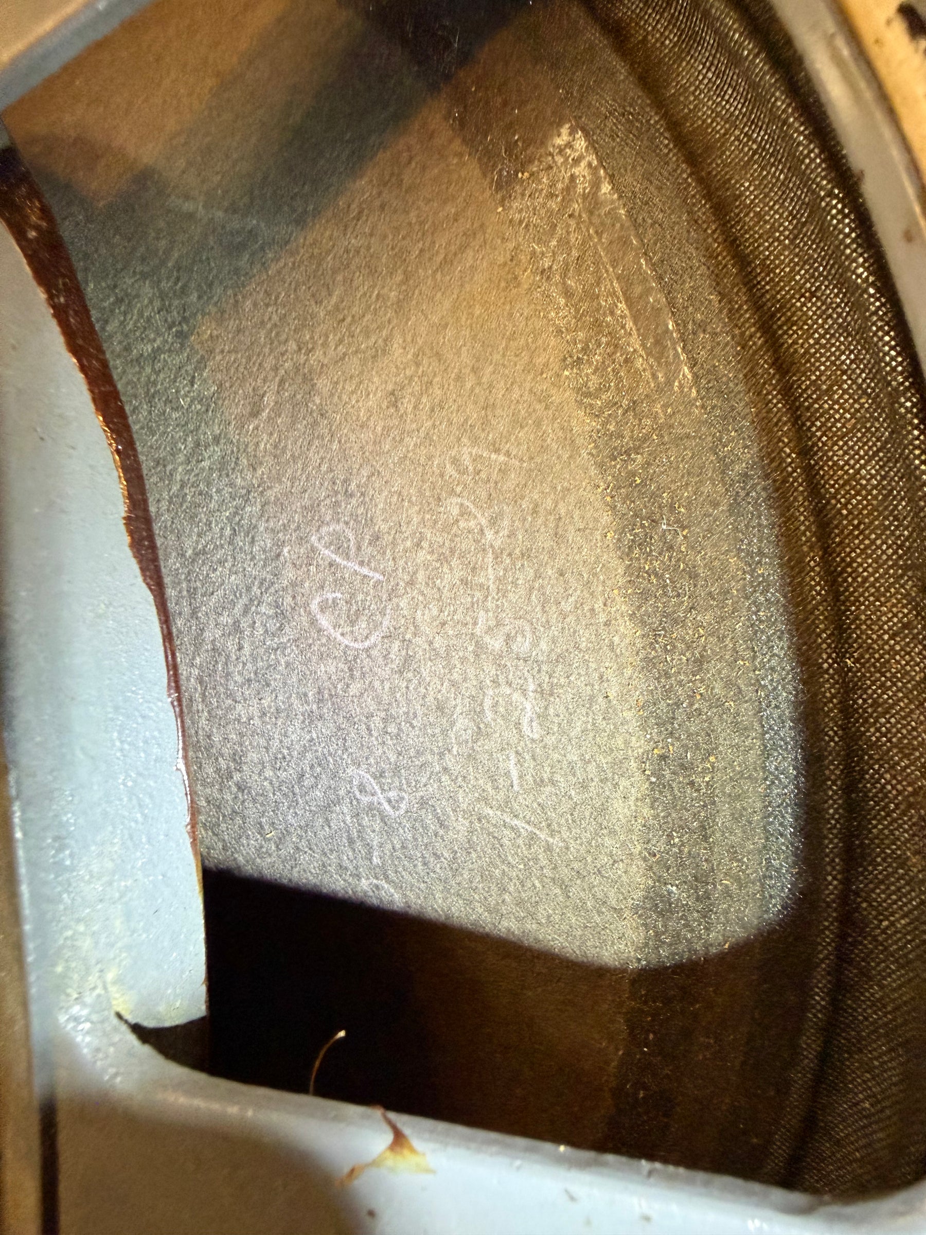 Close-up of a speaker cone, showing handwritten white markings on the light grey paper and a dark brown cloth surround.
