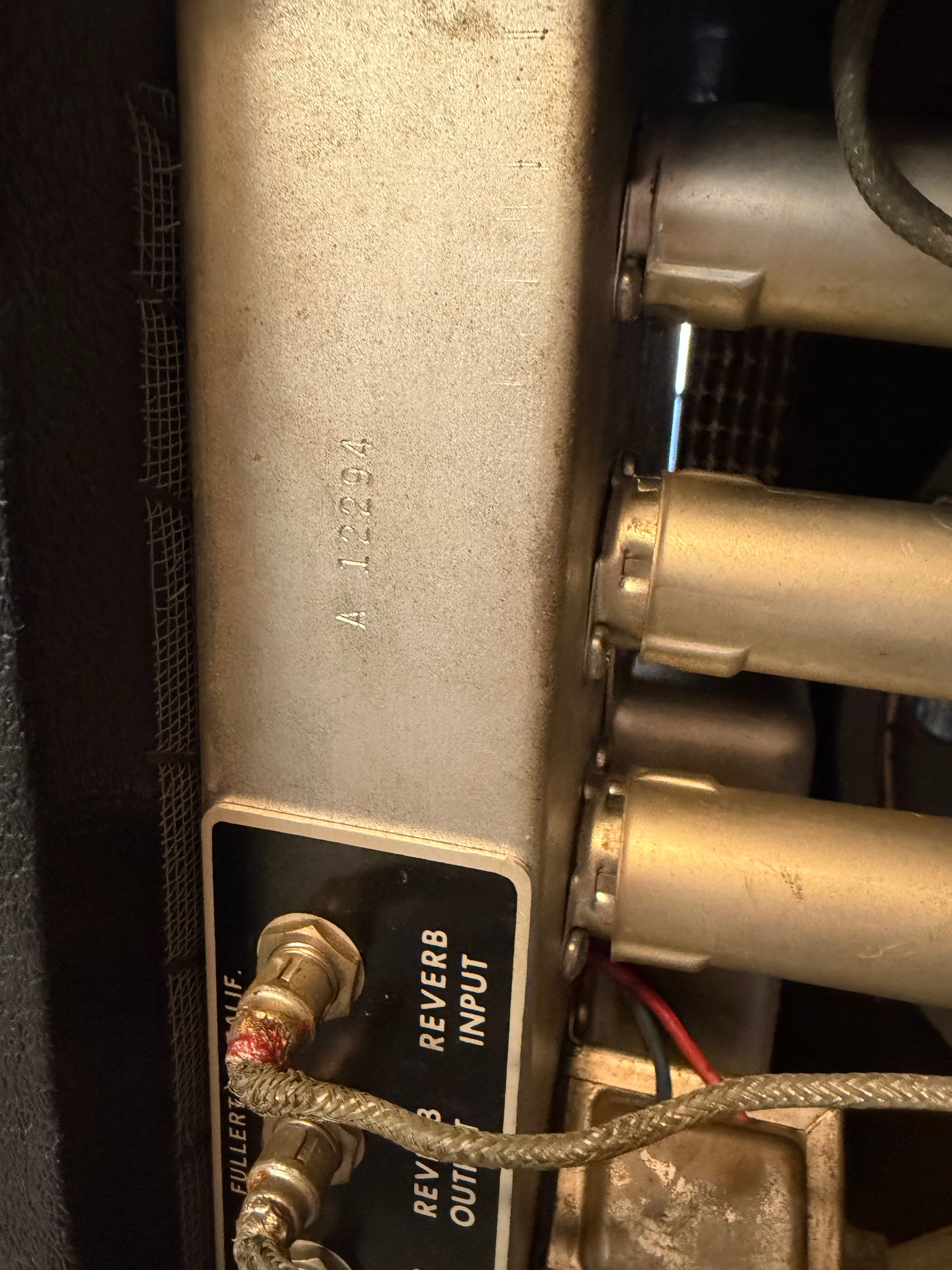 Close-up of the amp's silver chassis, showing the "A 12294" serial number, Reverb Input jack, and three vacuum tubes.