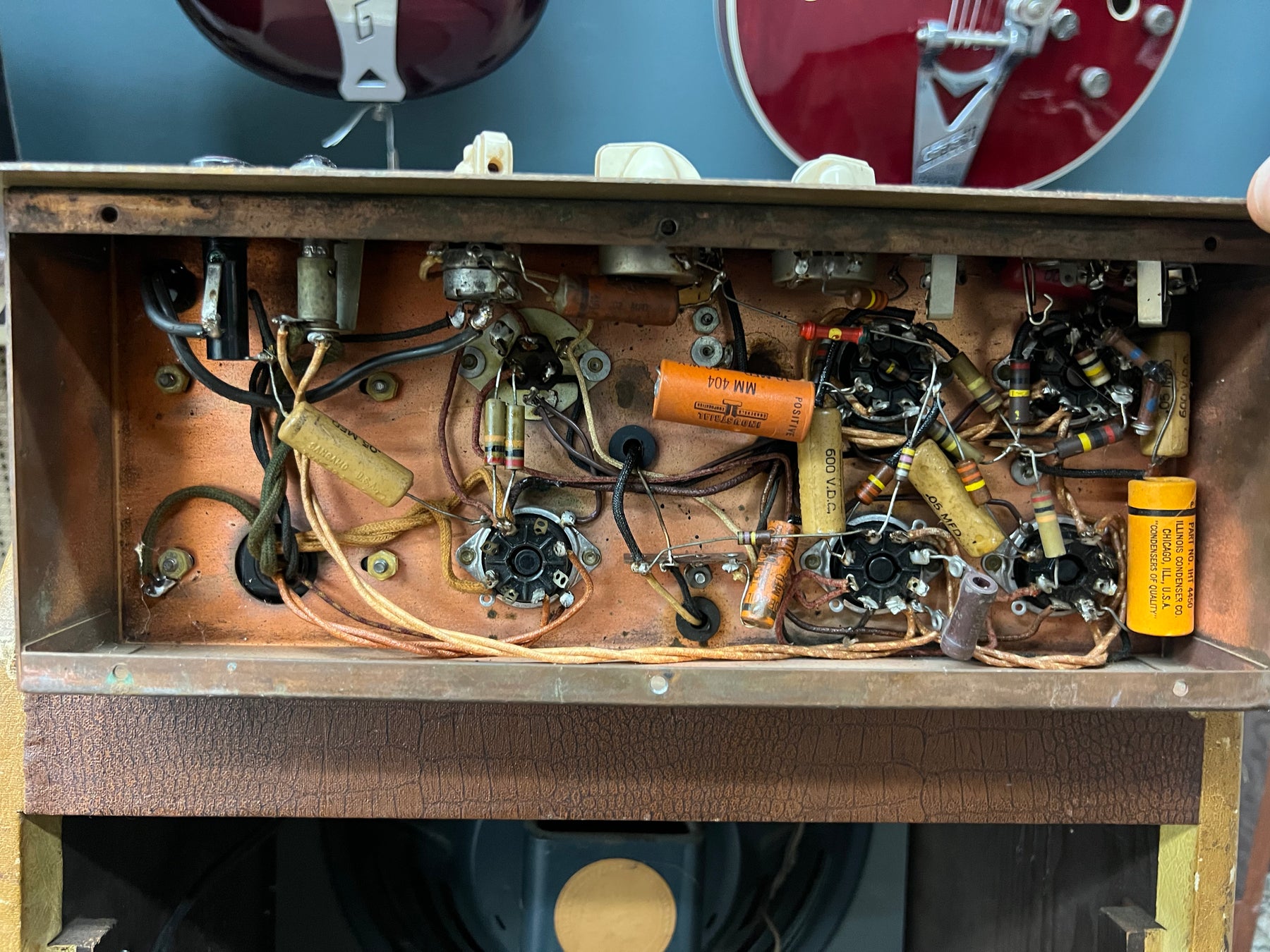 Overhead view of the amp's open chassis, revealing a copper-colored circuit board with various wires, capacitors, and tube sockets.