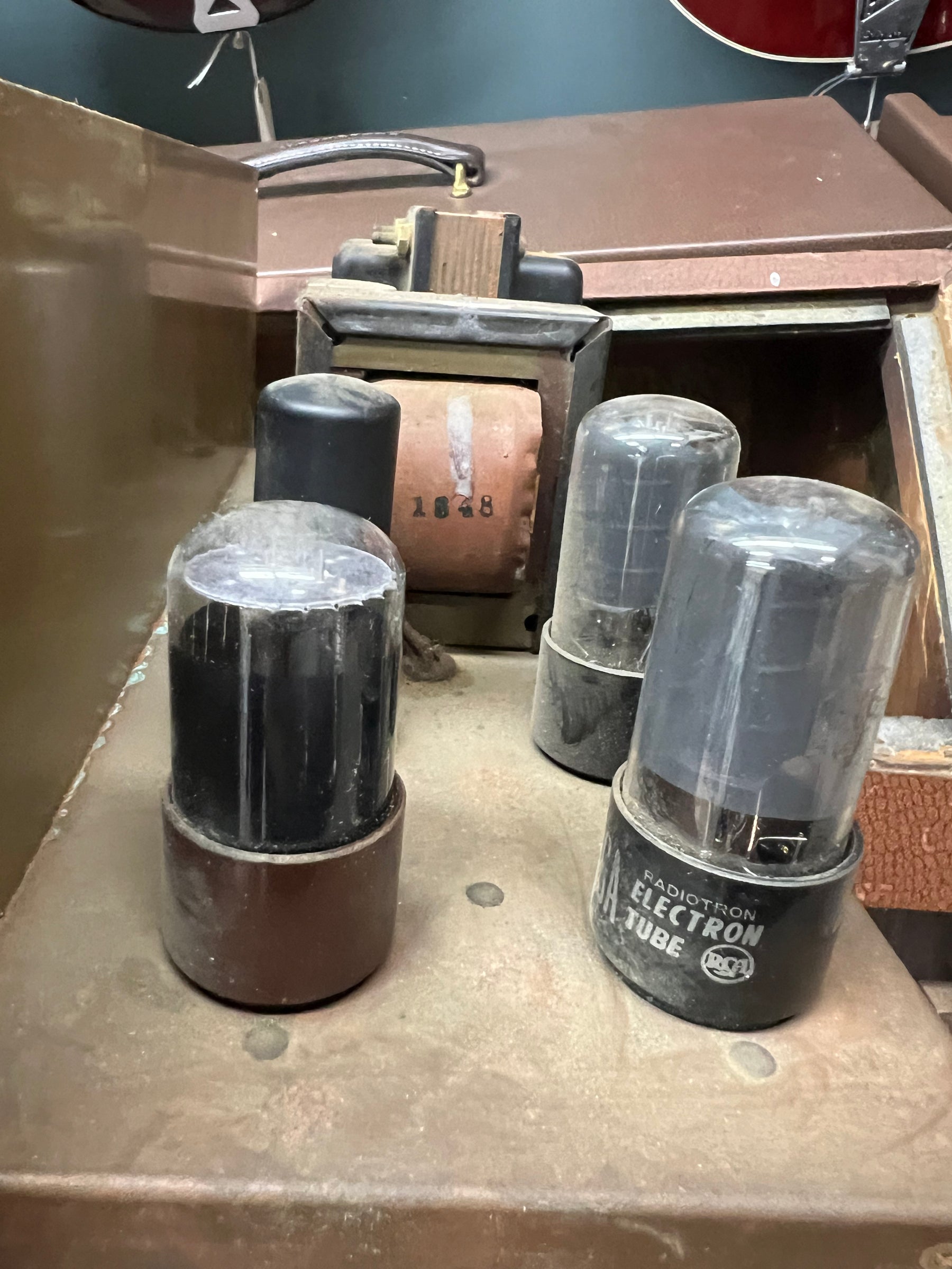 Close-up of the amp's dusty, tarnished metal chassis, showing three large vacuum tubes and a transformer with "1848" stamped on it.