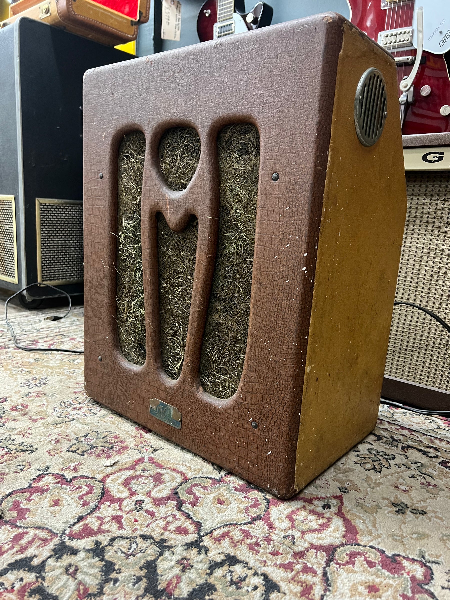 A vintage brown alligator-textured combo amp, angled to show its front grille with three vertical cutouts and a side vent.