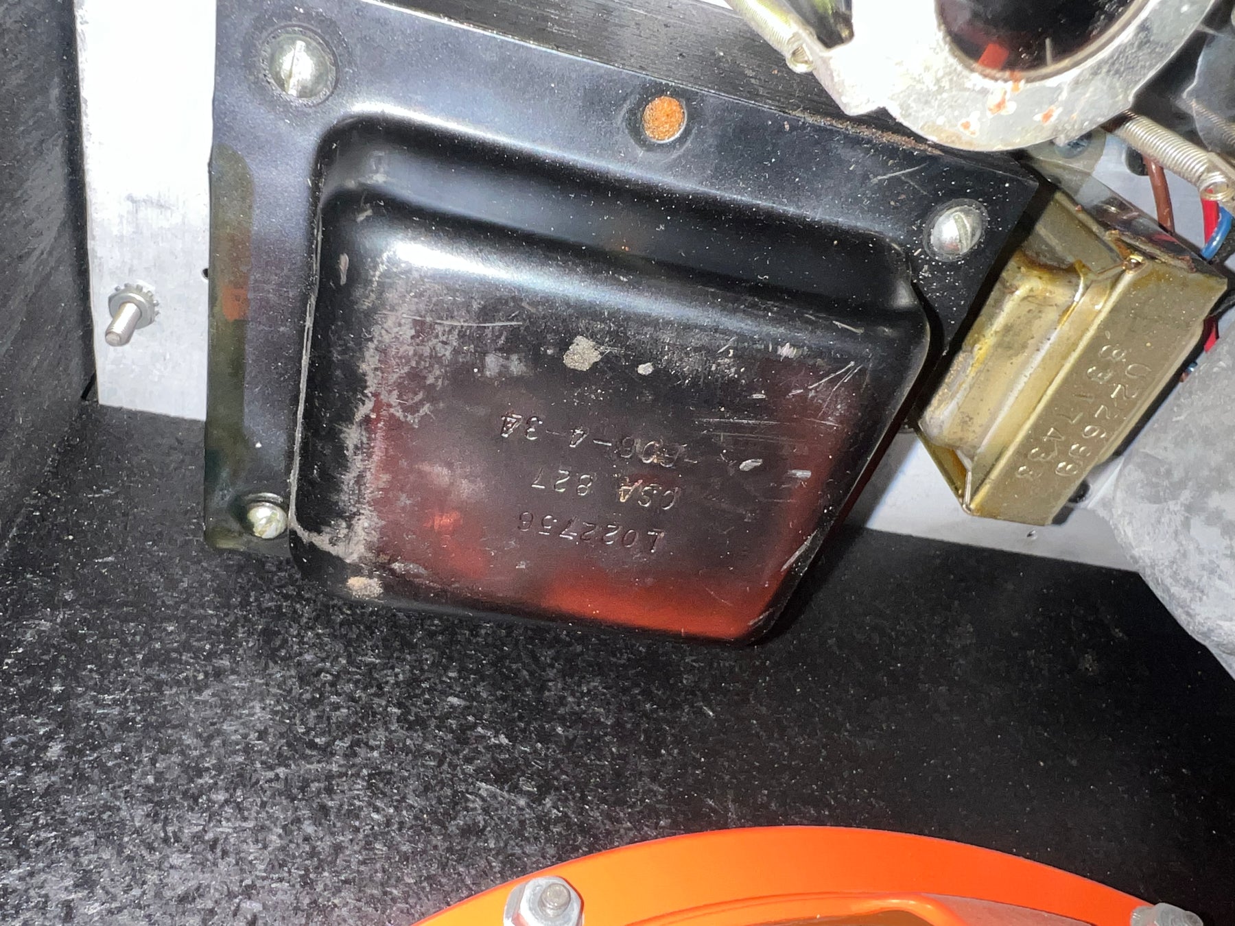 Close-up of internal components, showing a large black transformer with visible wear and a smaller gold-colored component.