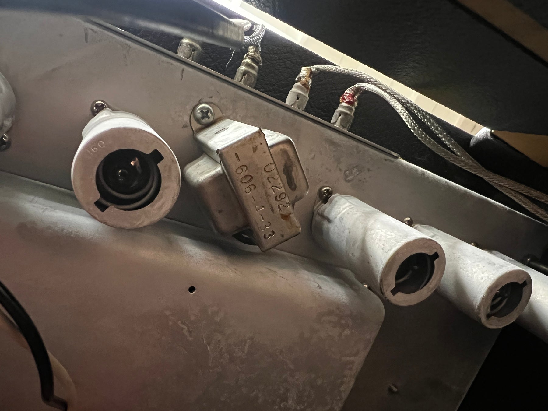 Close-up of the amp's silver chassis, showing three empty tube sockets, a metal transformer with visible numbers, and braided wires.