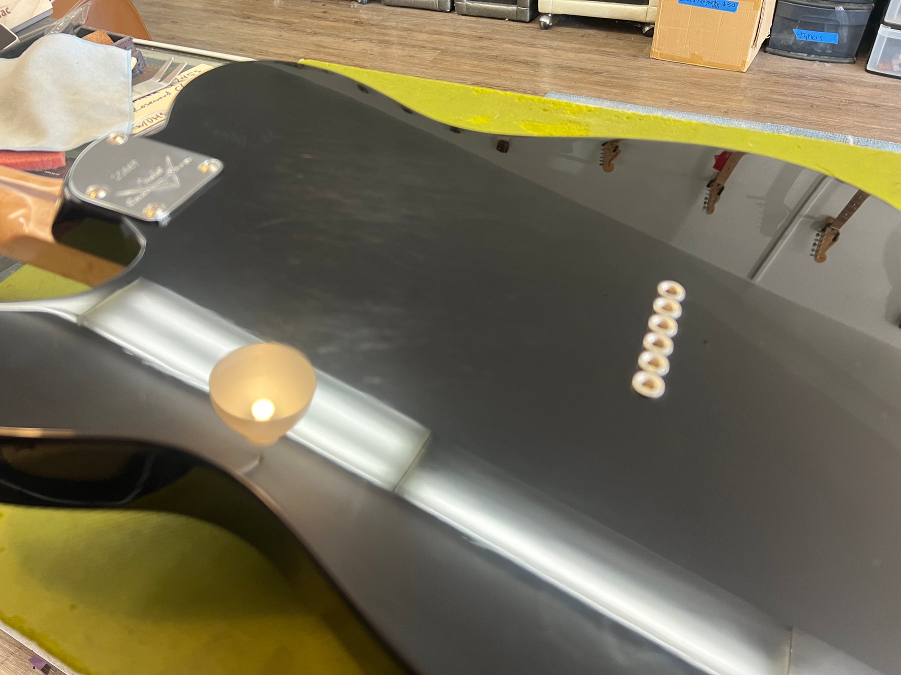 The black Telecaster's glossy back shows light scuffs, a chrome neck plate, and six cream-colored string ferrules.