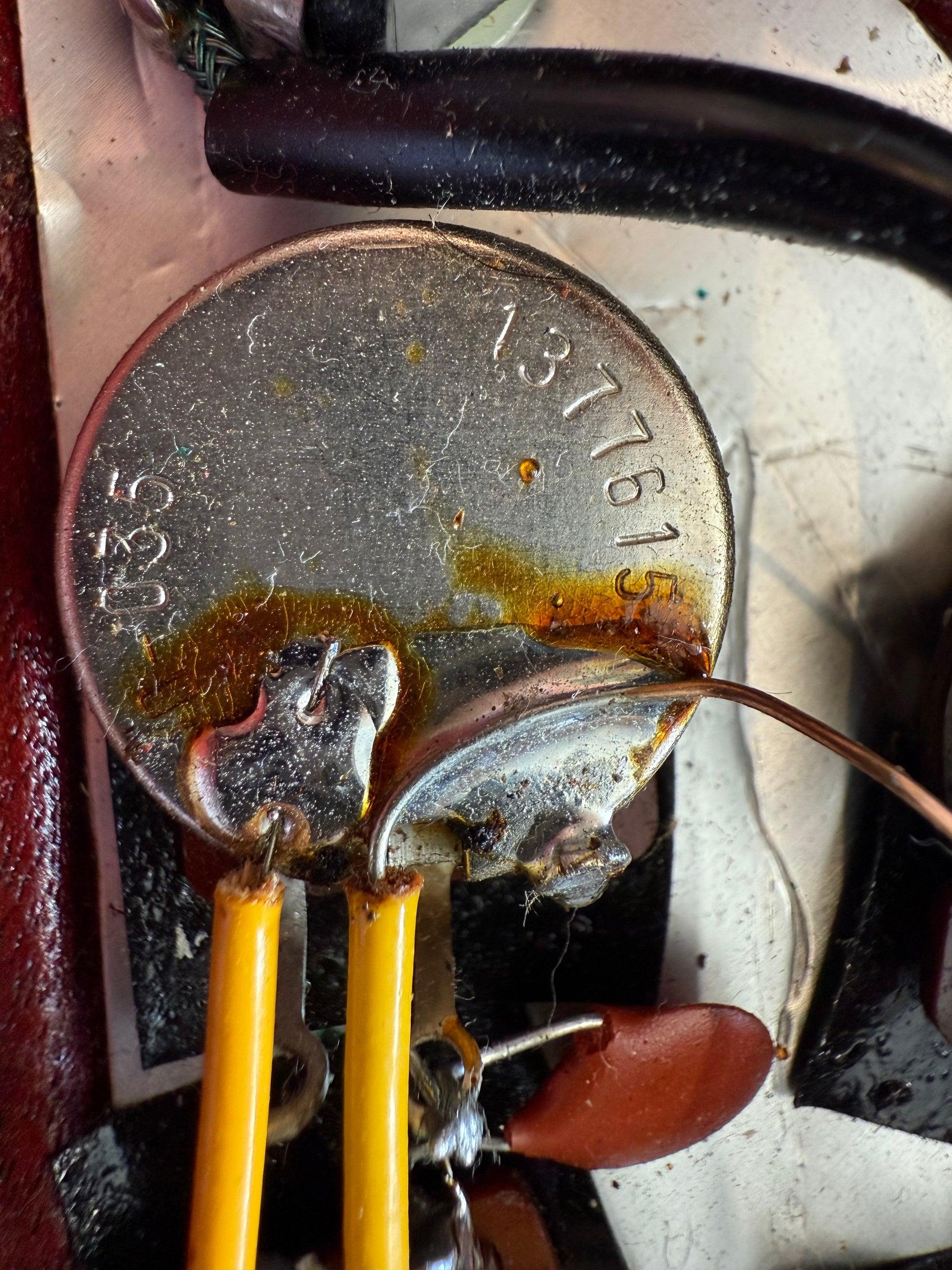 Close-up of a silver potentiometer with "1377615" and "520" stamped on it, showing aged solder joints and yellow wires.