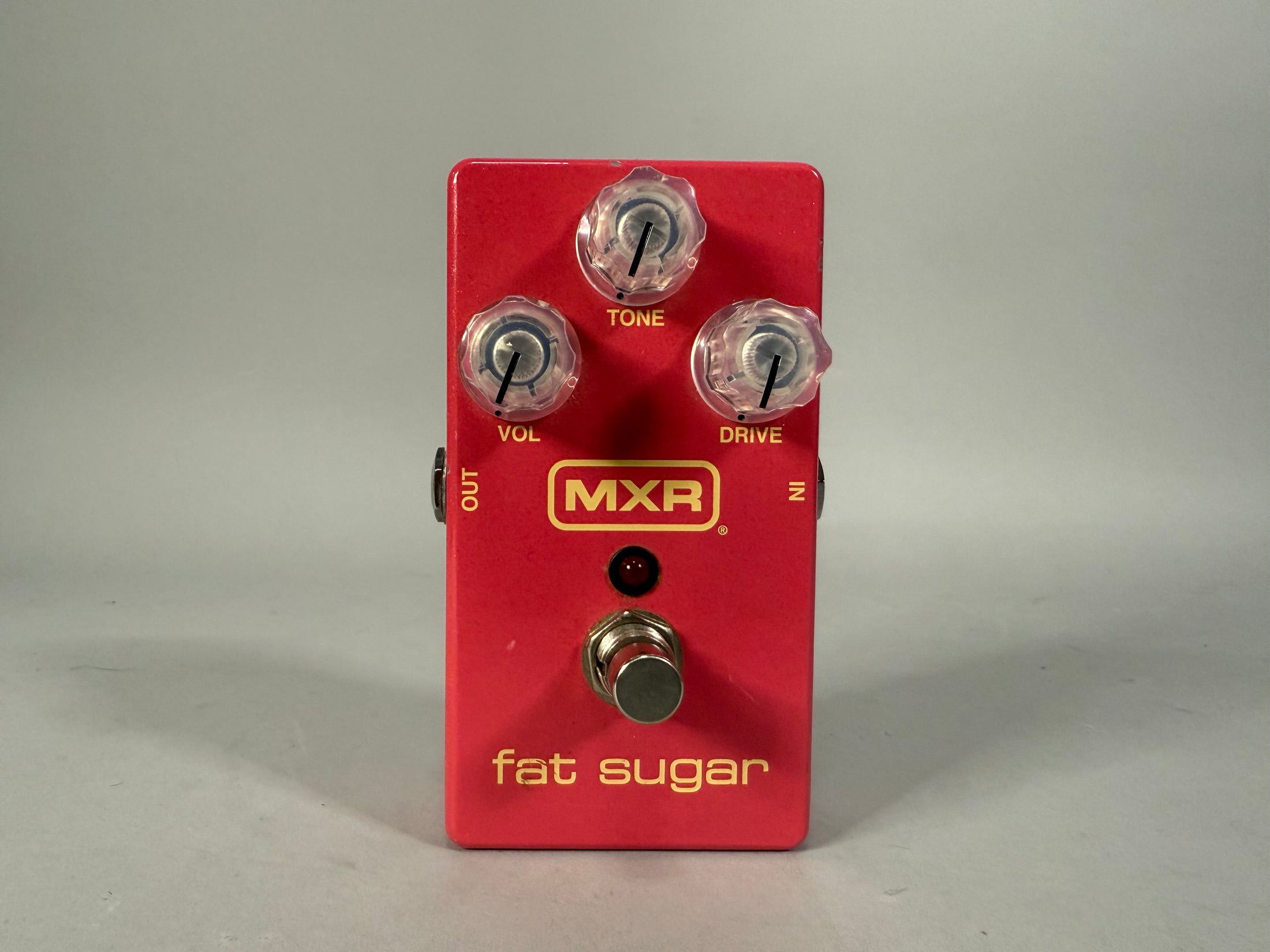 A red guitar pedal with three clear top-mounted control knobs labeled "Tone," "Vol," and "Drive," and a silver footswitch.