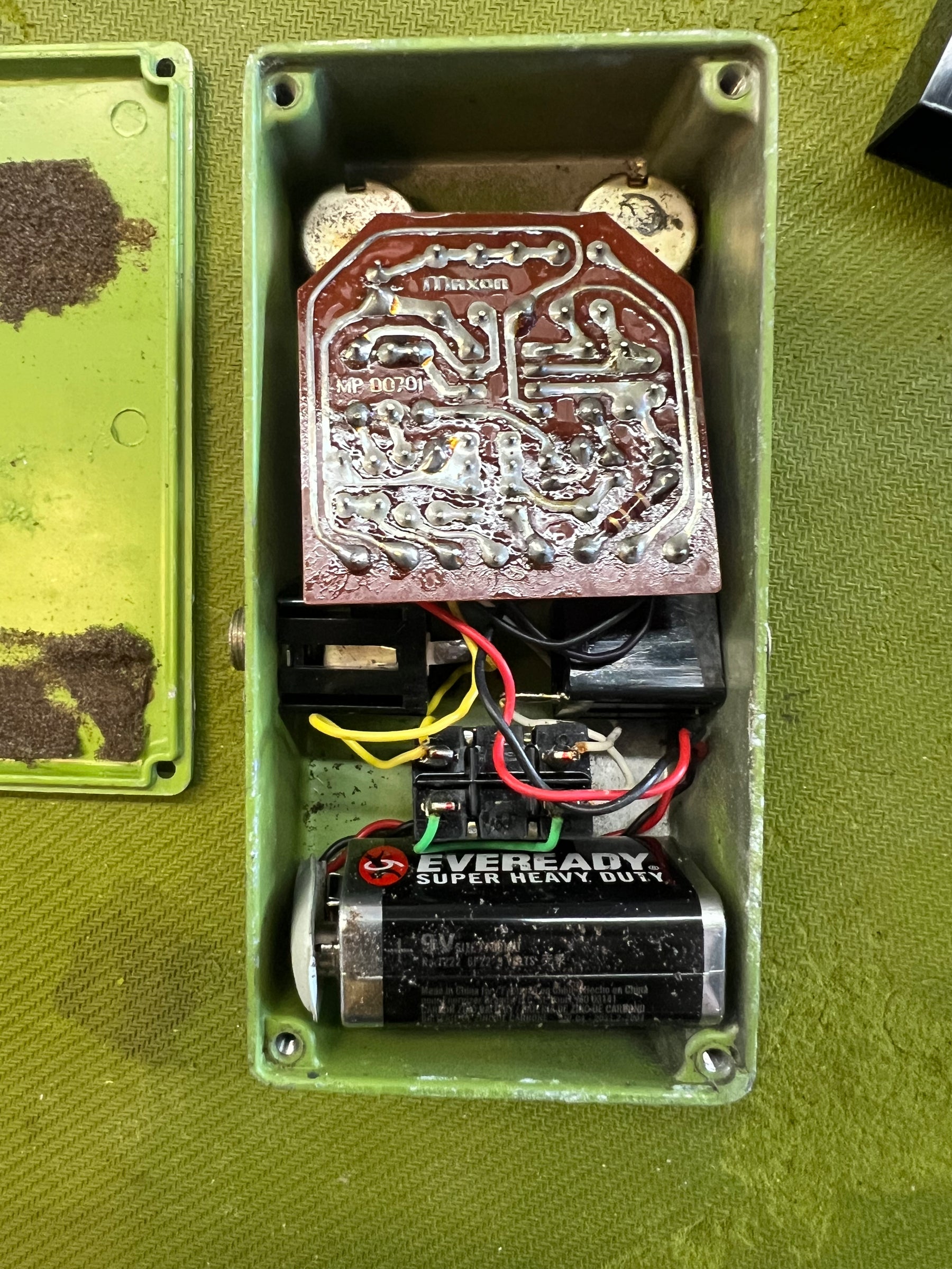 The pedal's green enclosure is open, revealing a circuit board, wiring, and a 9V Eveready battery.