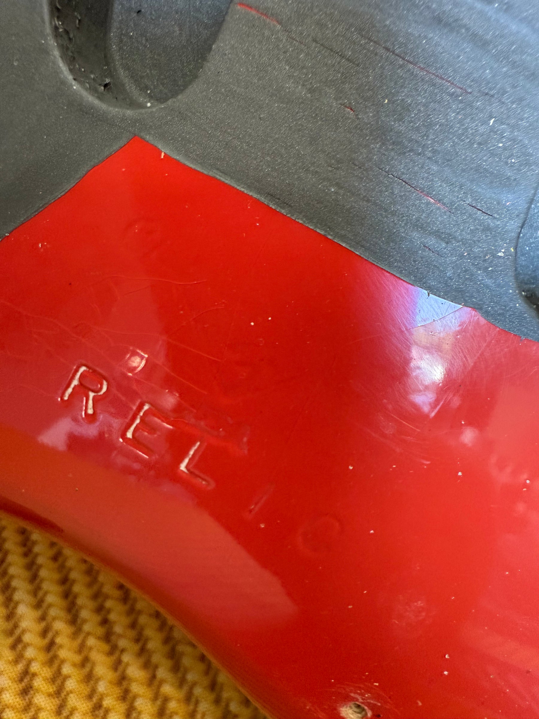Close-up of the guitar's Fiesta Red finish, showing "RELIC" stamped into the paint and light wear, with a black case lining.