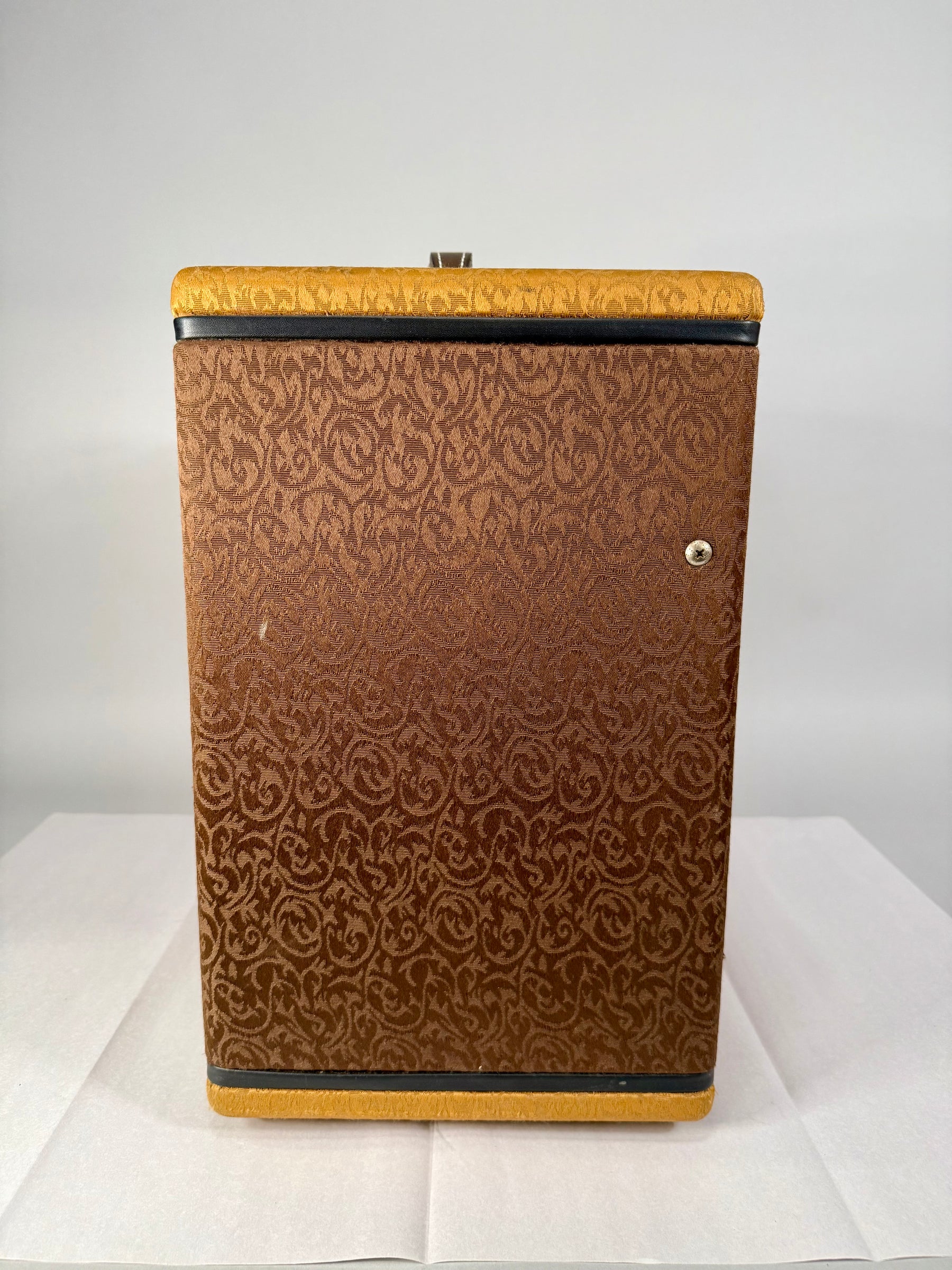 The amplifier's right side is covered in brown fabric with a swirling pattern, framed by black piping and gold textured trim.