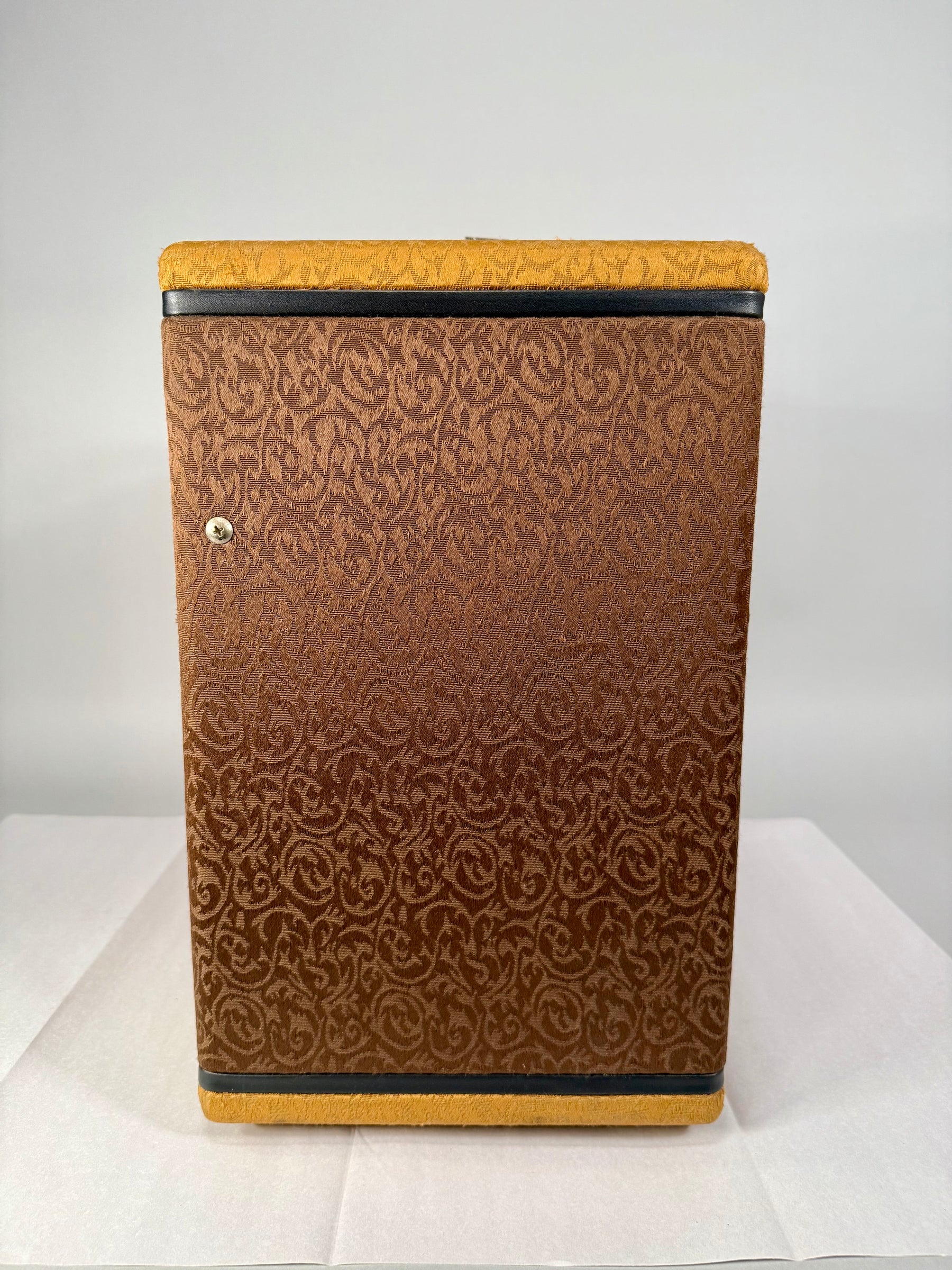 The right side of the amp, covered in brown patterned fabric with gold top and bottom edges, and a single silver screw.