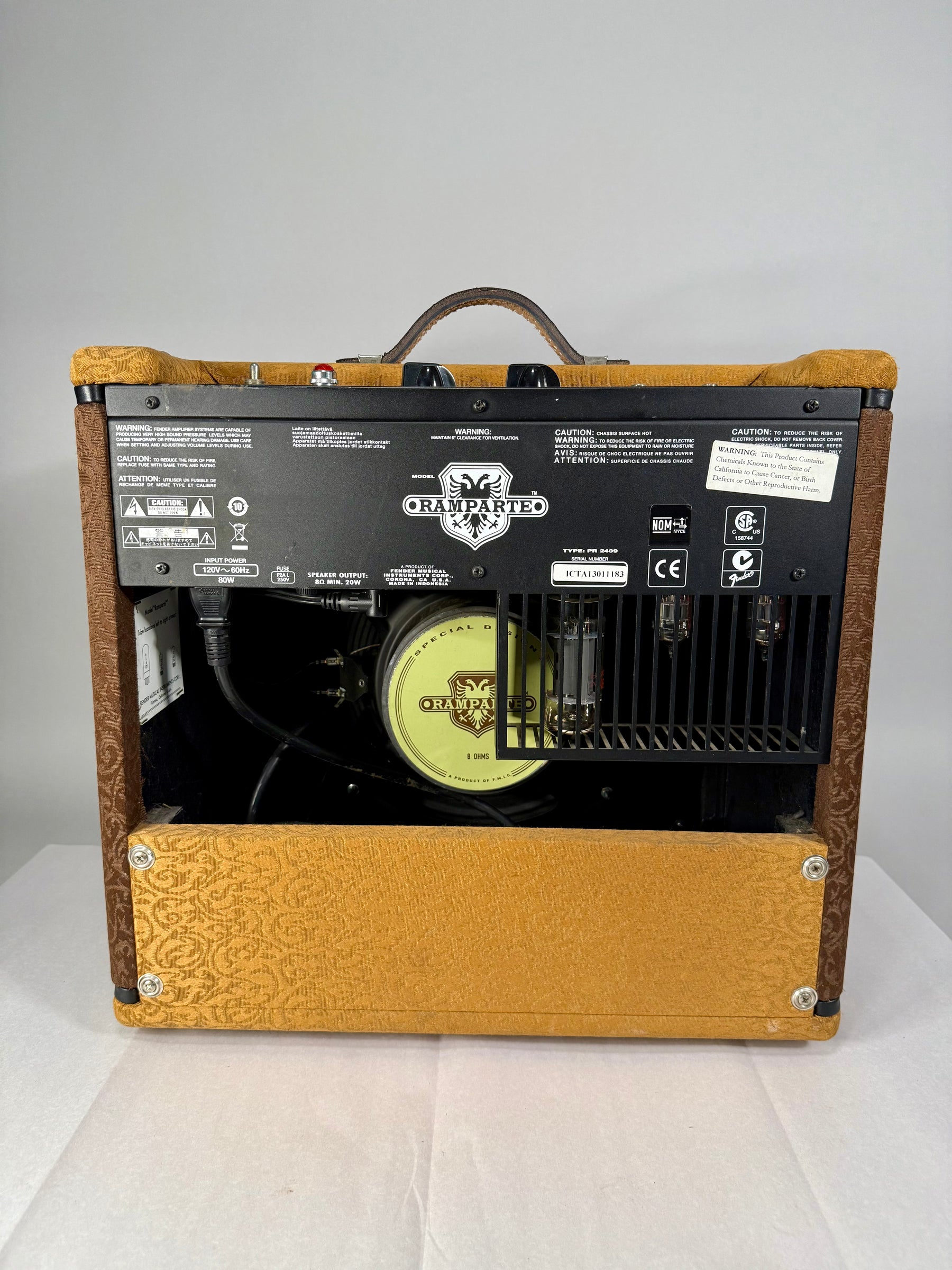 The amp's back panel is visible, showing the black metal chassis with warning labels, power input, and exposed tubes and speaker.