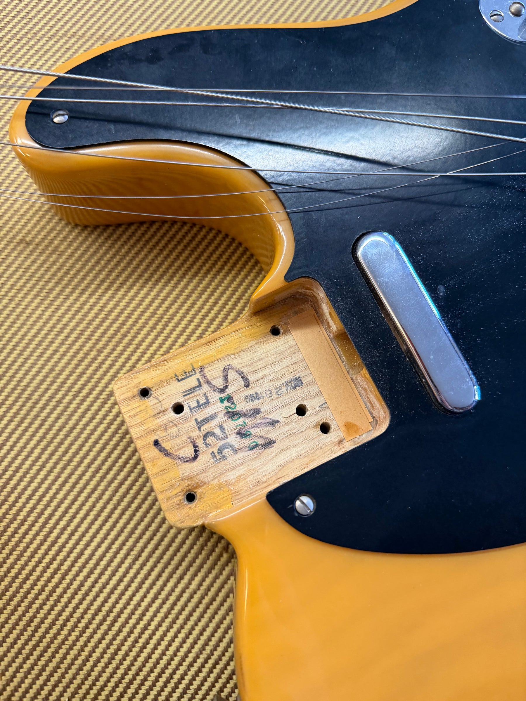 Close-up of the guitar body, showing the neck pocket with visible markings, a black pickguard, and a chrome neck pickup.