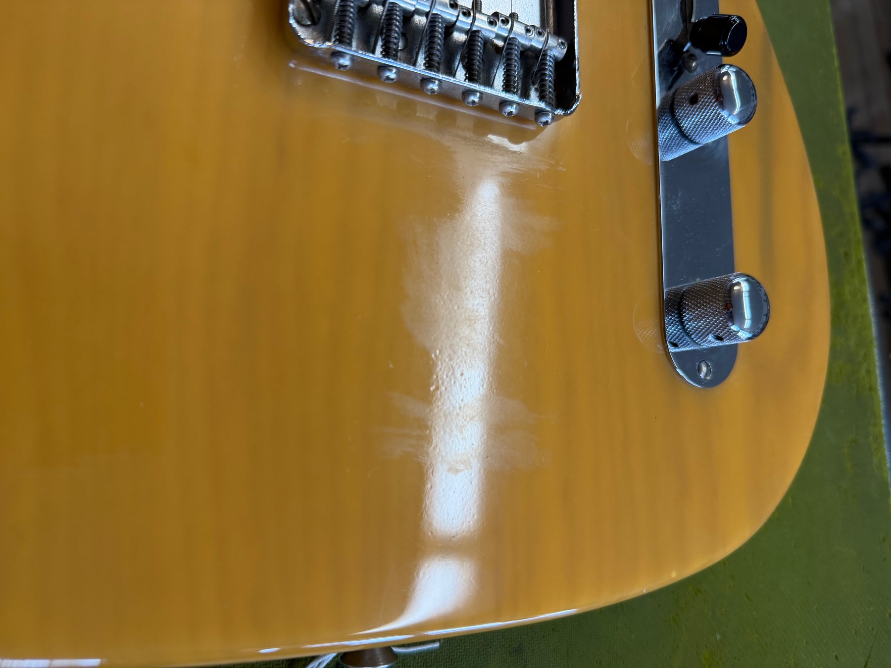 Close-up of the butterscotch blonde body, showing the chrome bridge and control plate with two knurled knobs and a switch, plus finish wear.