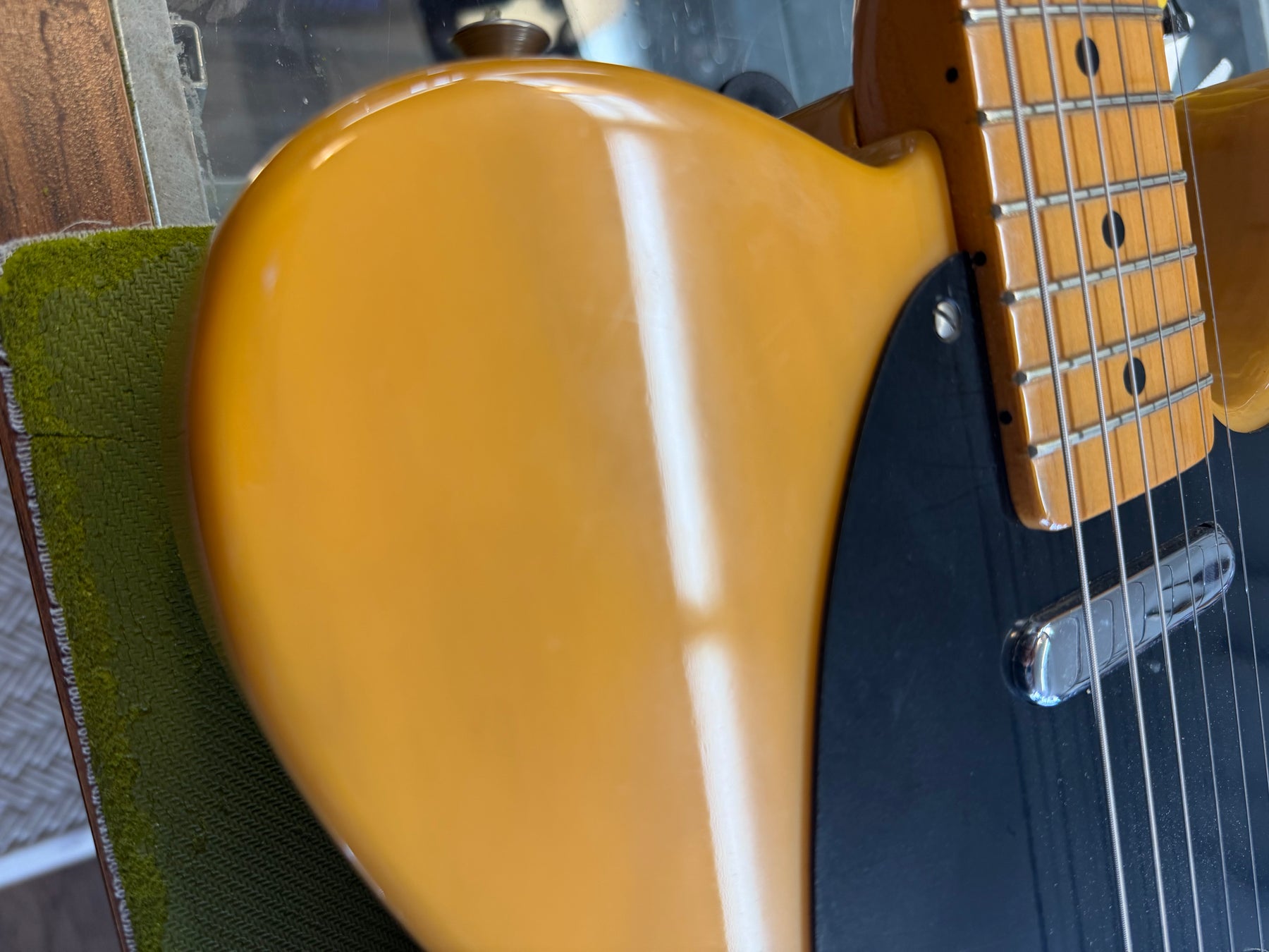 Close-up of the guitar's butterscotch blonde upper bout and black pickguard, showing light wear and a maple fretboard.