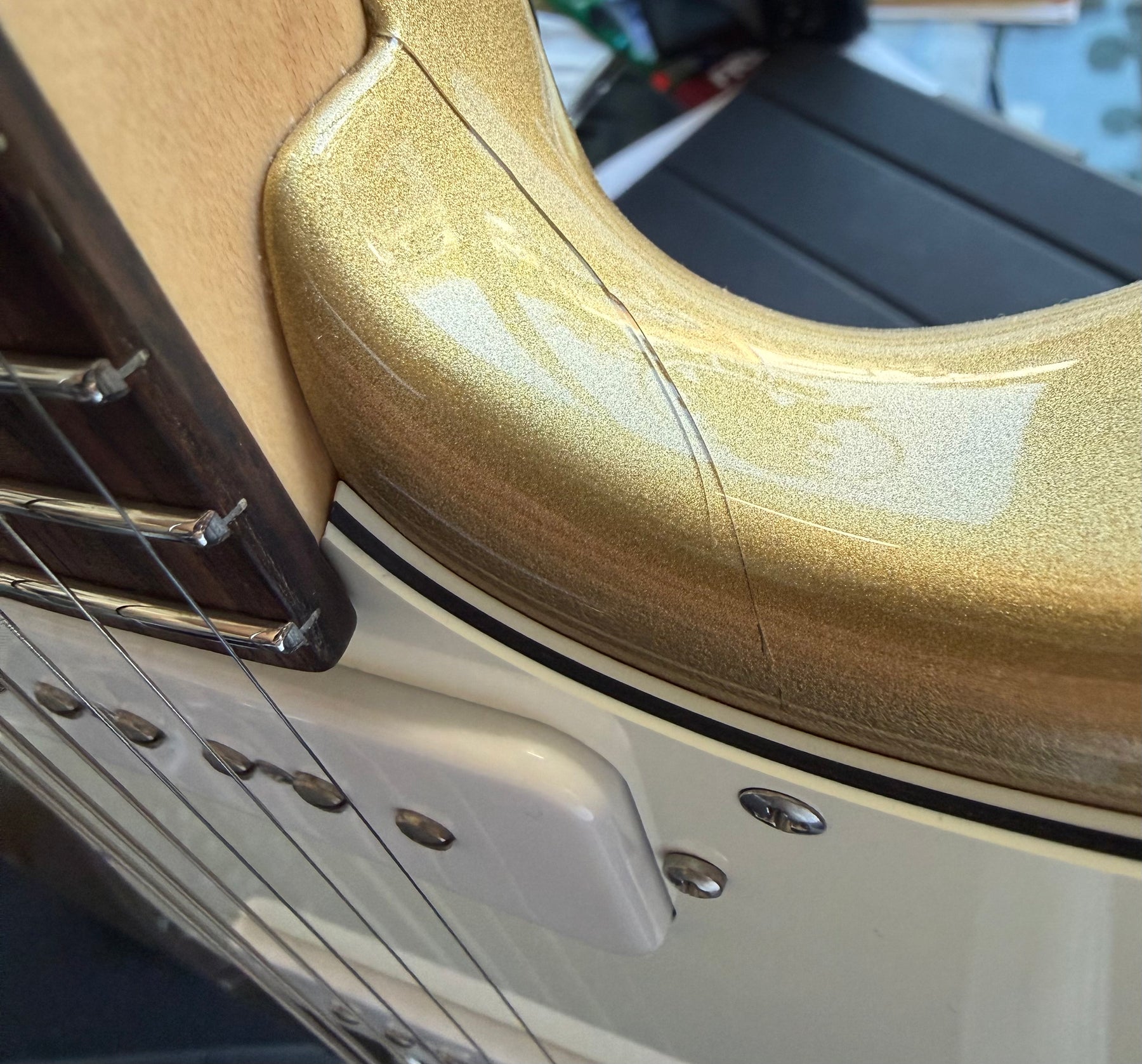 Close-up of the gold sparkle body's upper horn and neck joint, showing a white pickguard, two visible S90 pickups, and light wear.