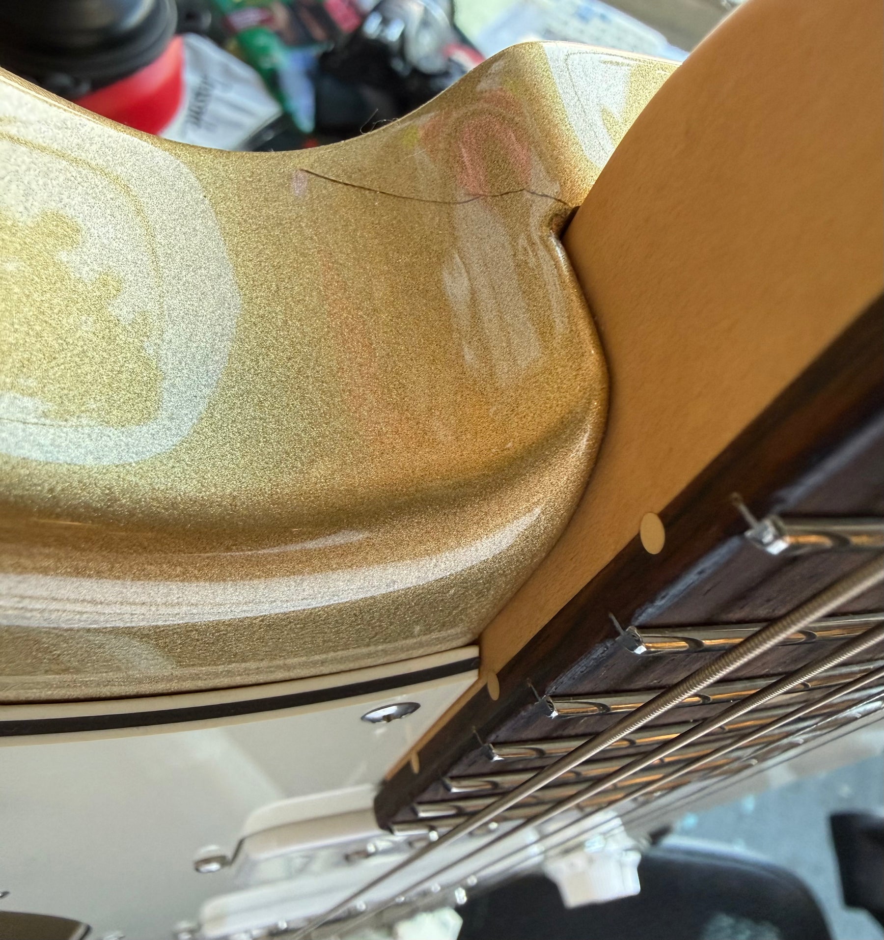 Close-up of the gold sparkle body and neck joint, revealing a finish crack near the neck pocket.