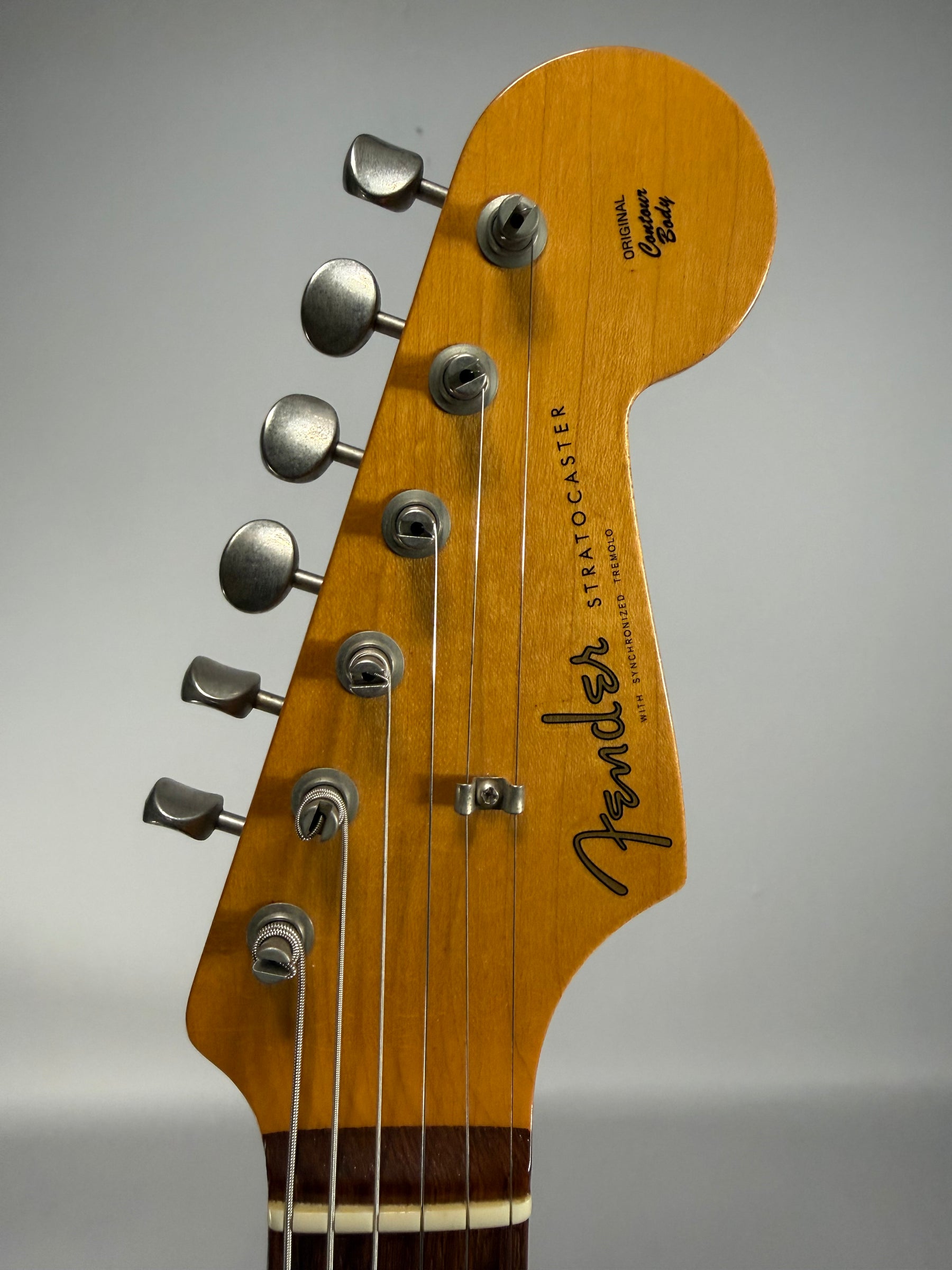 Close-up of the guitar's headstock, showing six vintage-style tuners, a string tree, and a light amber finish with some checking.