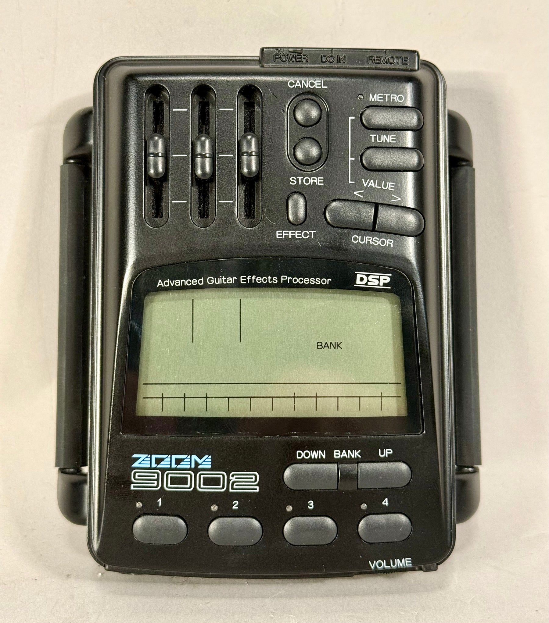 Top-down view of a black effects processor with three vertical faders, a large LCD screen, and various buttons.