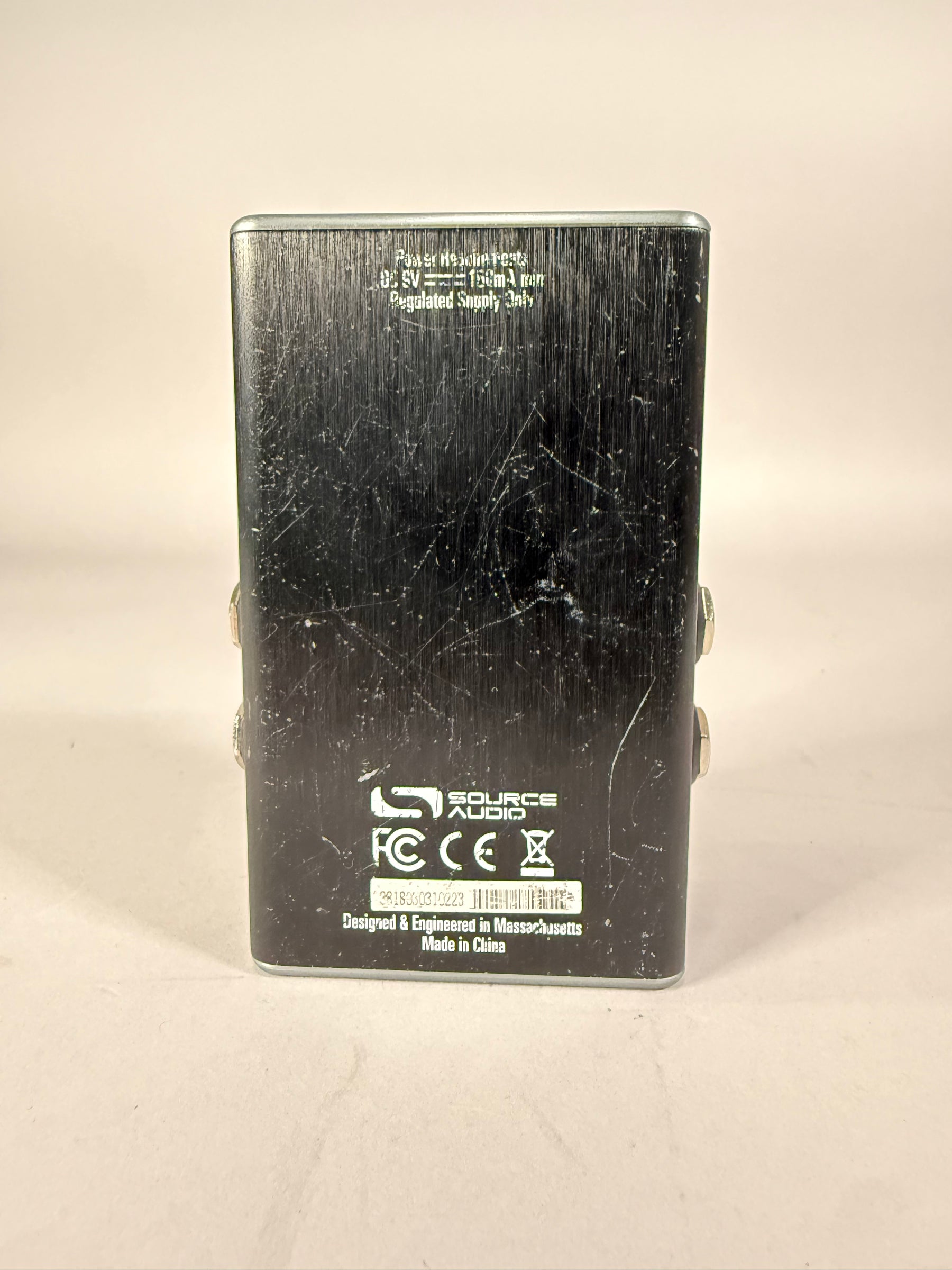 The pedal's brushed black metal underside is covered in many scratches and scuffs, with two silver jacks visible on the right side.