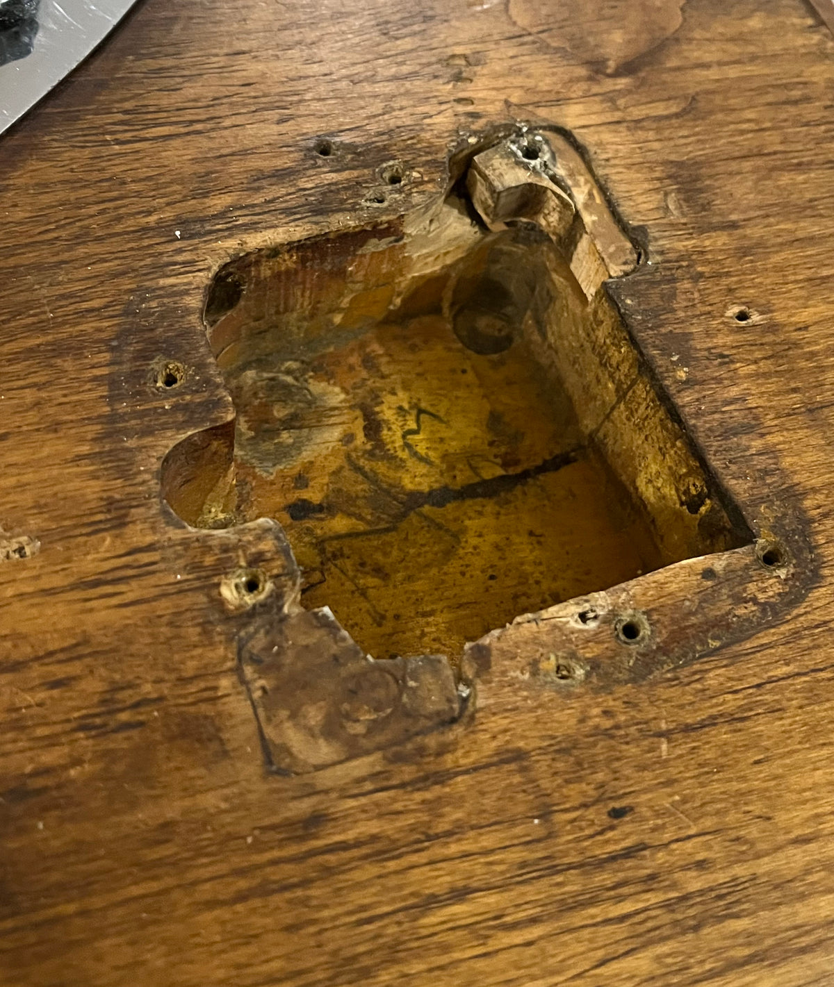 Close-up of the guitar's body cavity, showing raw wood, screw holes, and a yellow-painted interior with some writing.