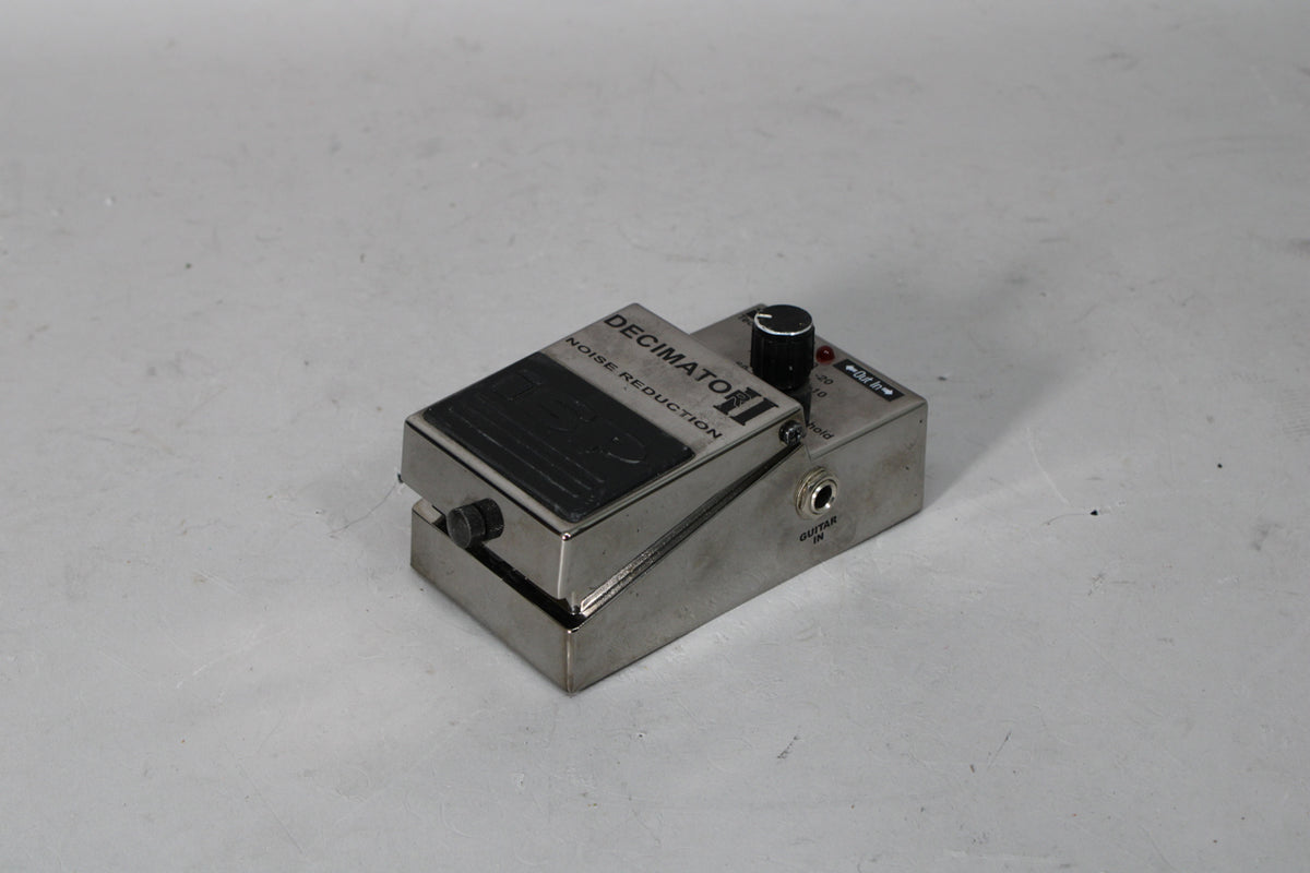 A silver metal guitar pedal, viewed from the front-right, with a black footswitch, a black knob, and a red LED.