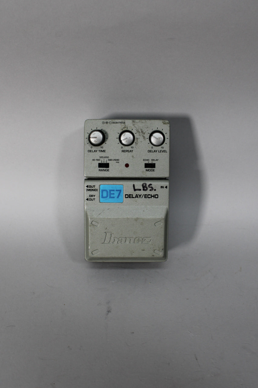 Top-down view of a light grey delay pedal with three silver knobs, two black switches, and visible surface wear.