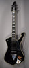 Full-length, angled view of a glossy black electric guitar with a unique body shape, chrome hardware, and pearloid block inlays.