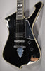 Close-up of a black electric guitar with a glossy finish, showing the body, neck, two humbuckers, and three control knobs.