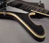 Close-up of the glossy black body, showing the cream binding with abalone inlay, chrome pickguard, and part of the fretboard.