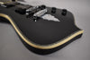 The black guitar body, with a cream and abalone binding, is angled to show the chrome bridge and tailpiece.