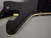 Close-up of the guitar's lower body, showing the glossy black finish and cream binding along the edges, with a strap button visible.
