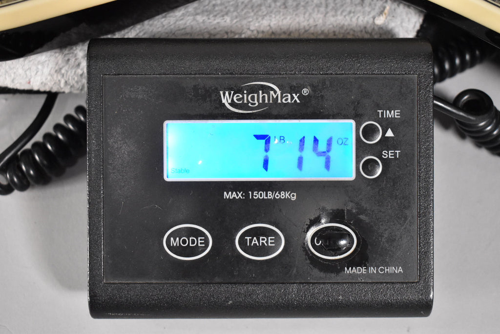 A black digital scale displays "7 LB 14 OZ" in blue, with a guitar neck visible at the top left.