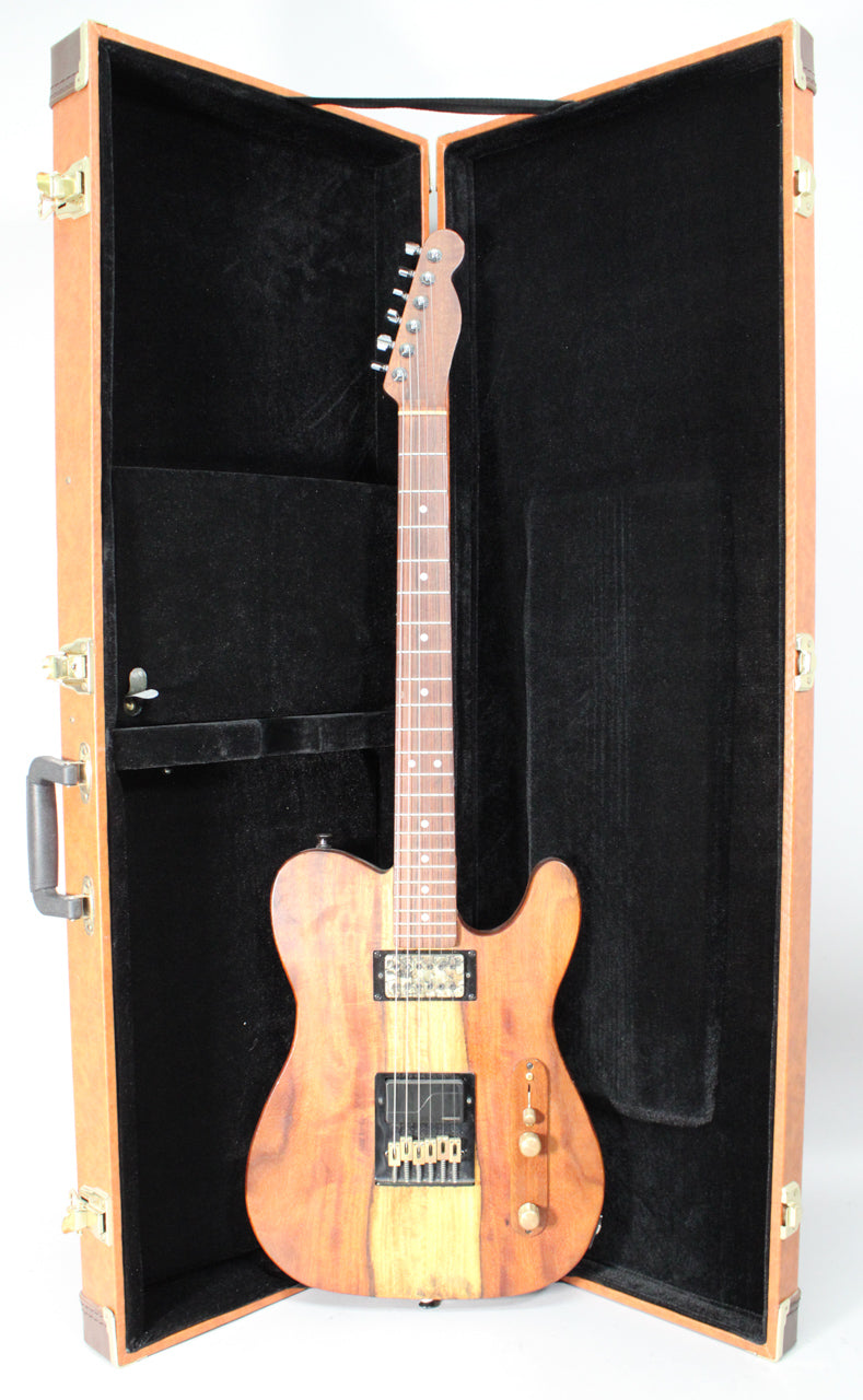 Full view of a natural wood T-style guitar with a dark rosewood fretboard, two humbucker pickups, and brass hardware, standing in its open hard case.
