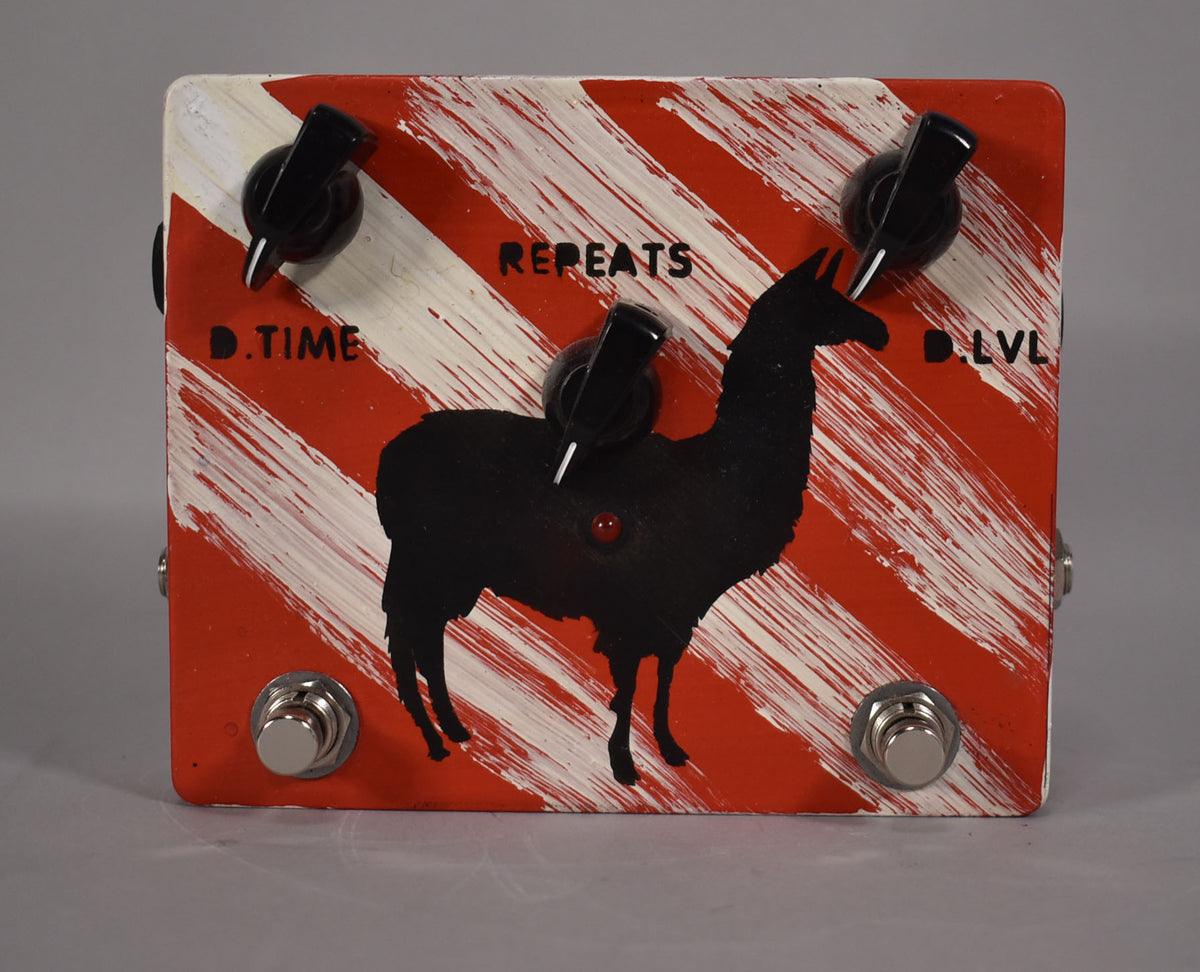 Top-down view of a red and white striped pedal with a black llama silhouette, three black knobs, and two footswitches.