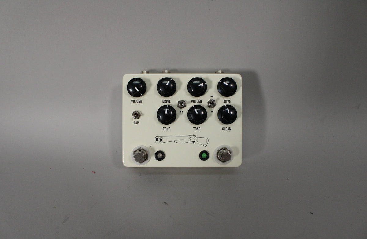 Cream-colored pedal with eight black knobs, two footswitches, a green LED, and a shotgun graphic, viewed from directly above.