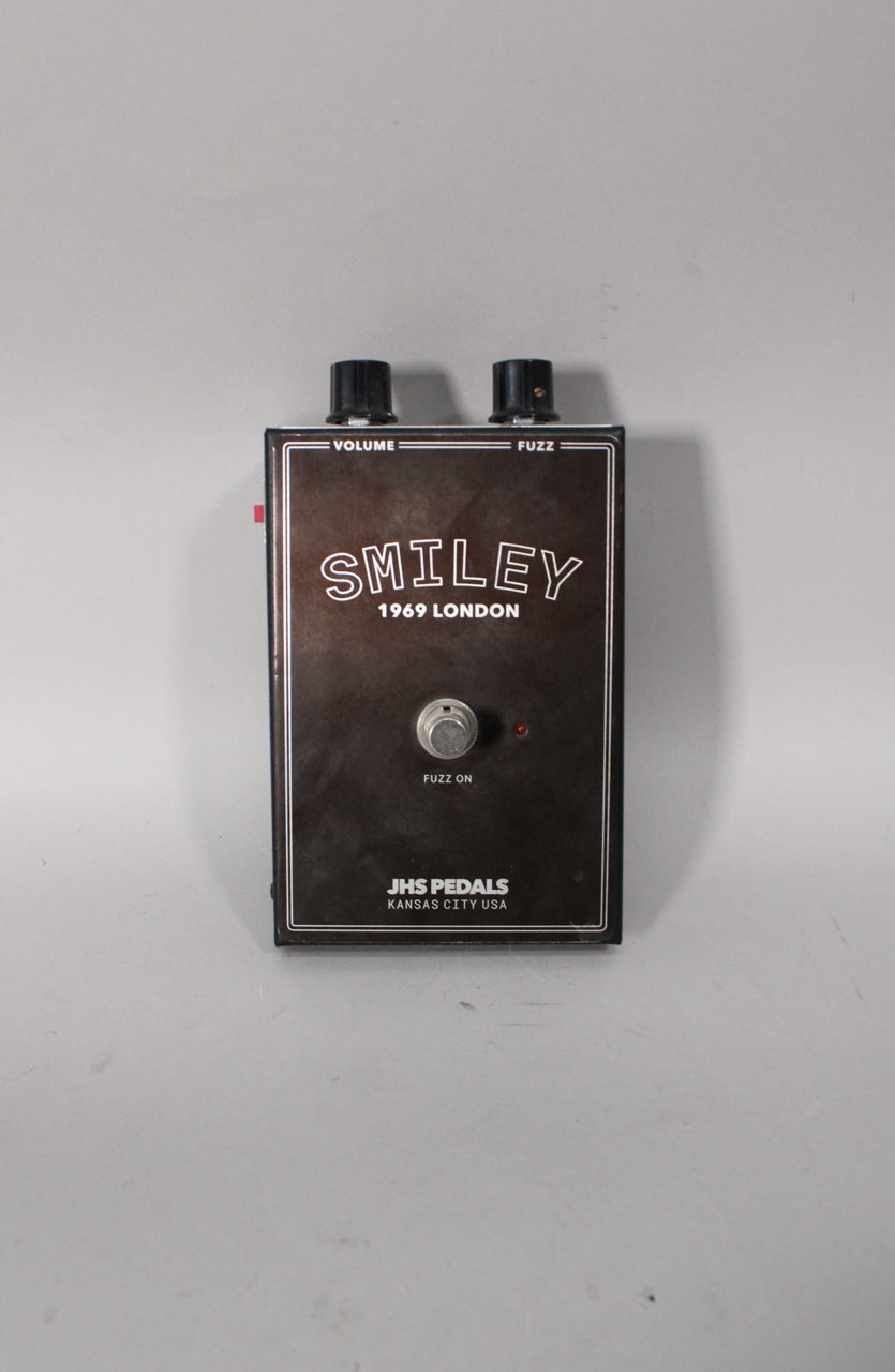 A dark brown rectangular fuzz pedal with two black control knobs, a silver footswitch, and a small red indicator light.