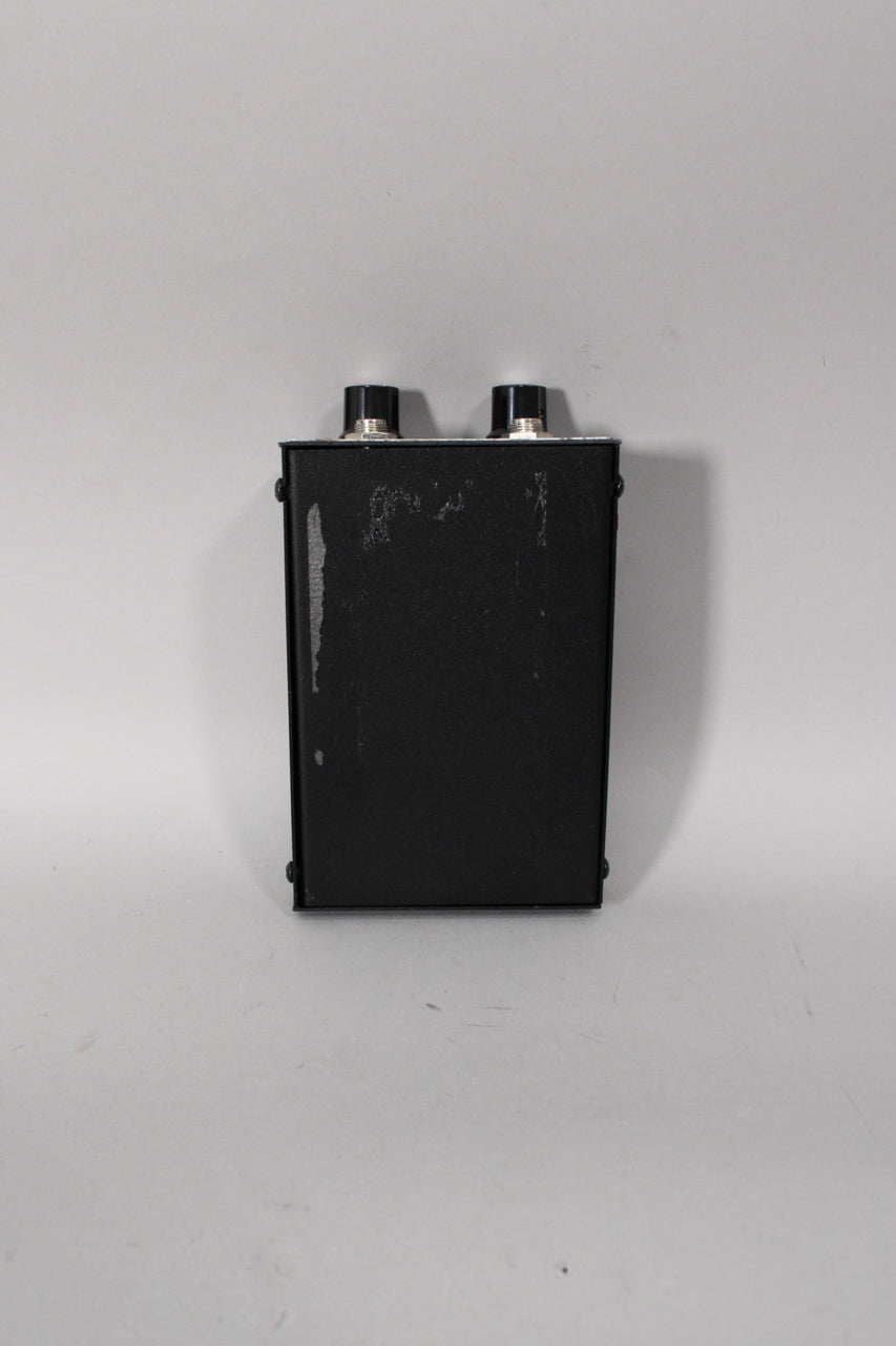 The black rectangular fuzz pedal is viewed from the top, showing two black control knobs and visible wear on the textured finish.