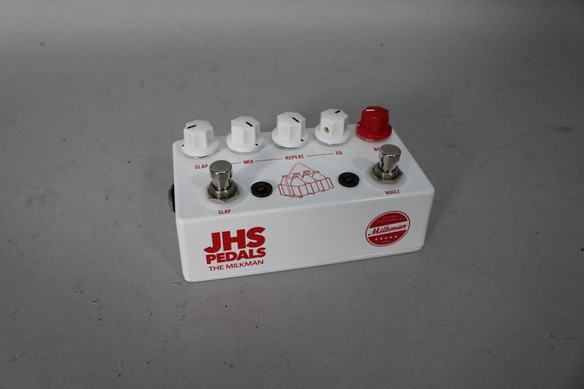 A white guitar pedal with red lettering, five white knobs, one red knob, and two silver footswitches, viewed from a slight angle.