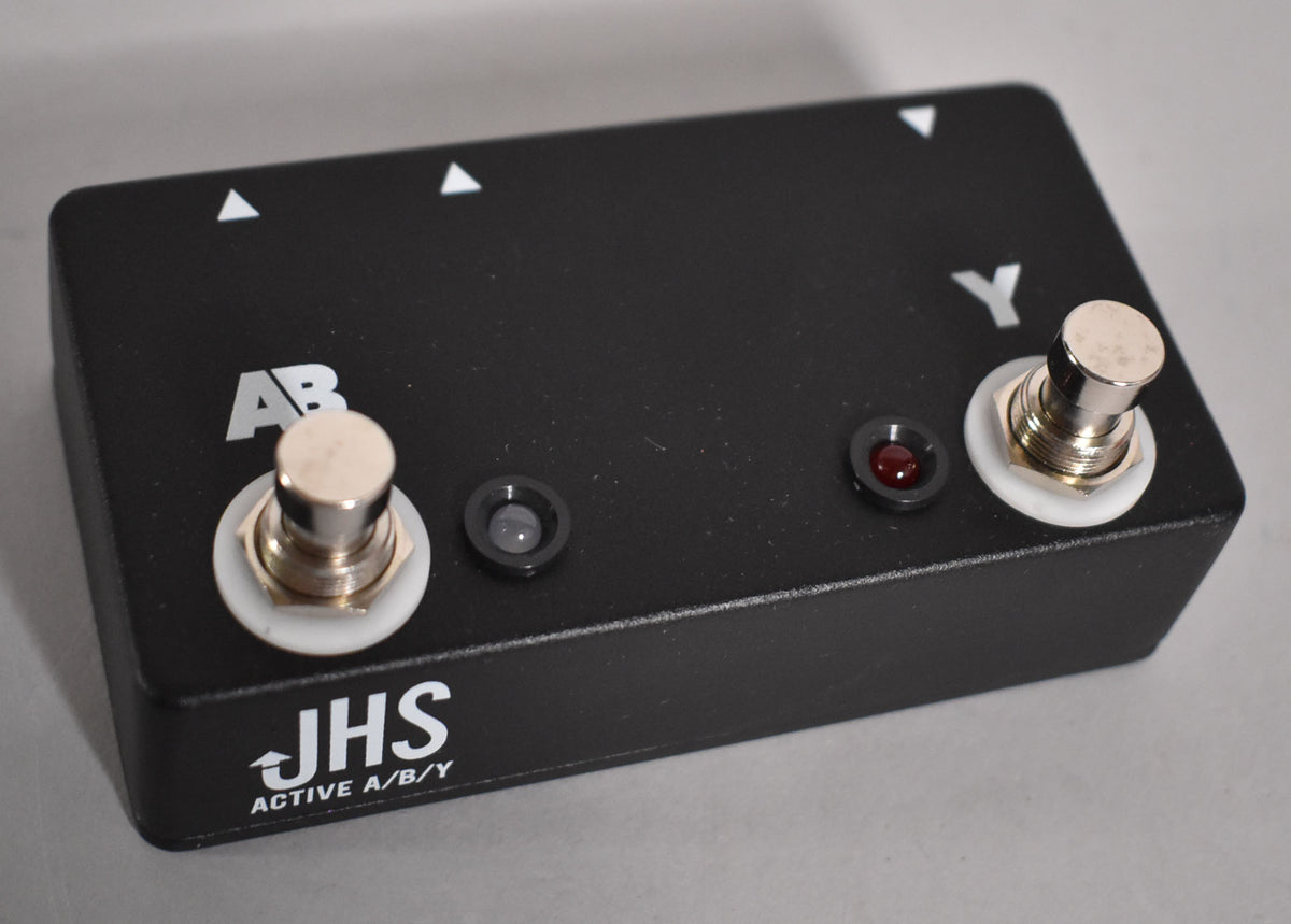 A black rectangular pedal with a textured finish, two footswitches, and two small indicator lights, viewed from a slight angle.