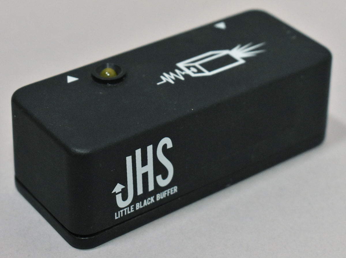 A black rectangular pedal with a matte finish, a small yellow LED, and white graphics of a guitar jack and a lightning bolt.